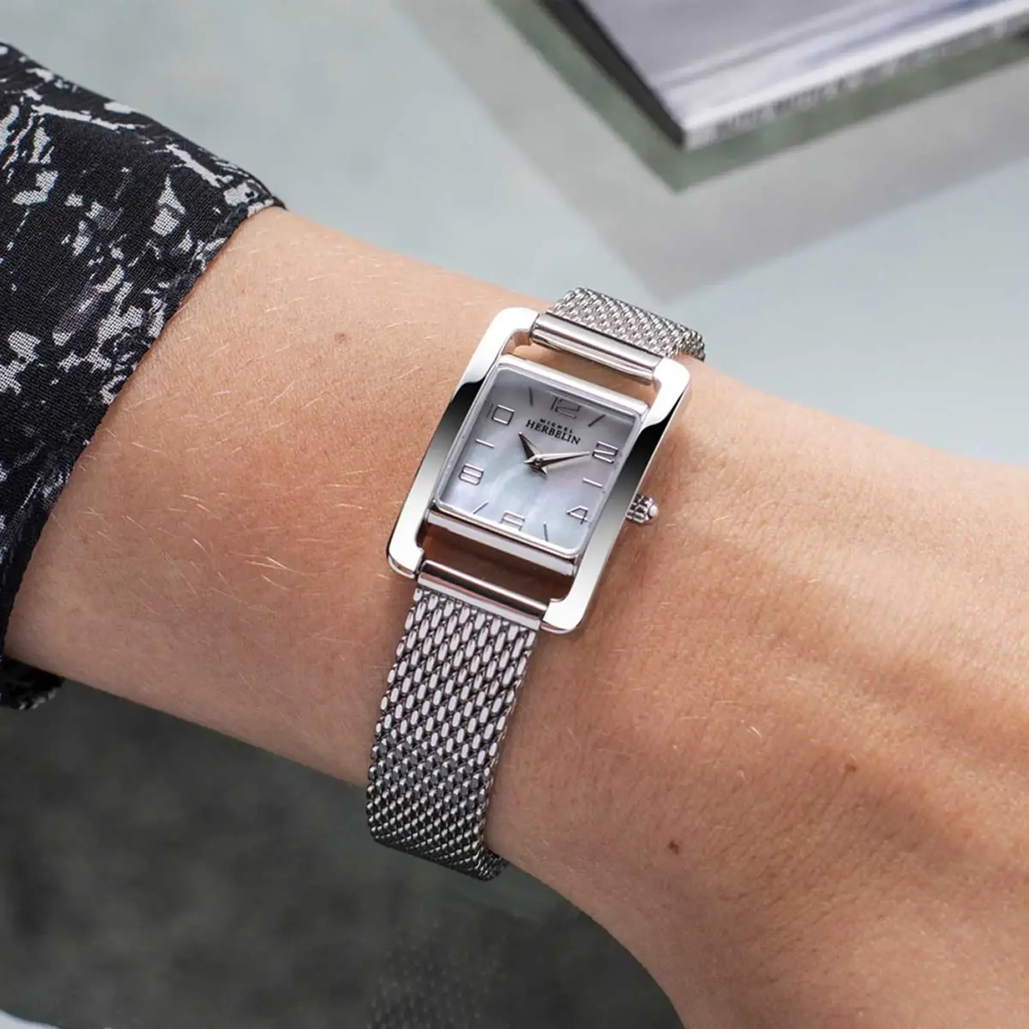 Au poignet féminin, cadran nacre blanche et bracelet acier visibles