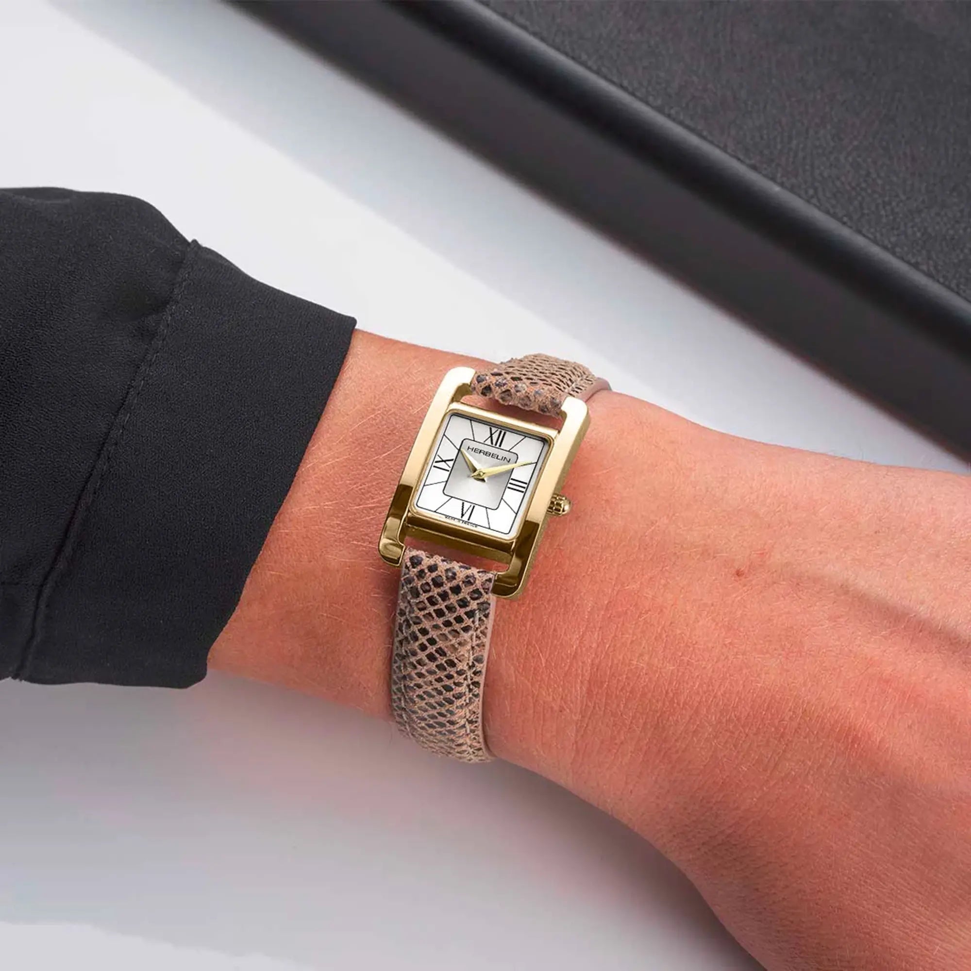 Au poignet féminin, cadran argent et bracelet cuir visibles