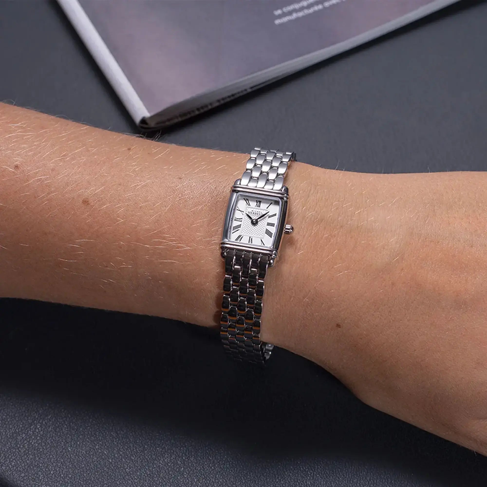 Au poignet féminin, cadran argent guilloché et bracelet acier visibles