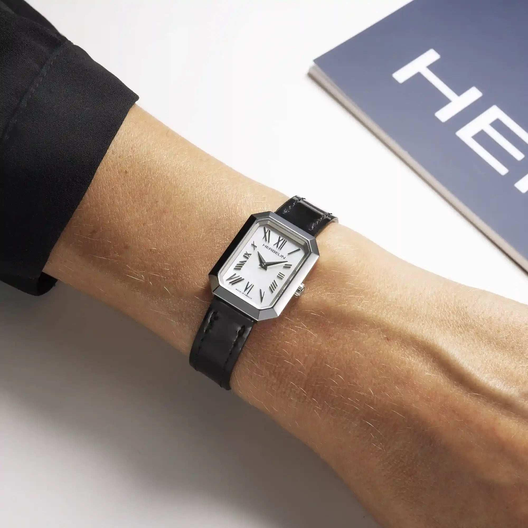 Au poignet féminin, cadran nacre blanche et bracelet cuir visibles