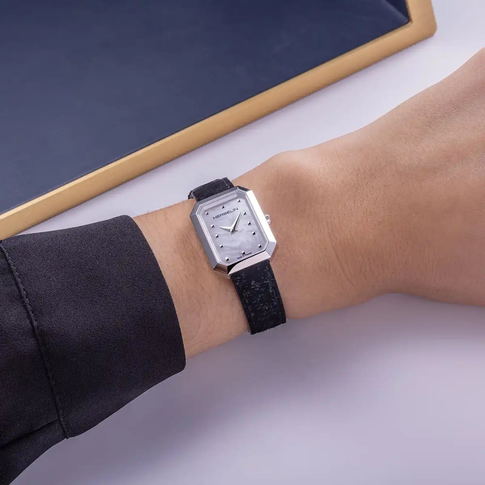 Au poignet féminin, cadran nacre blanche et bracelet cuir visibles