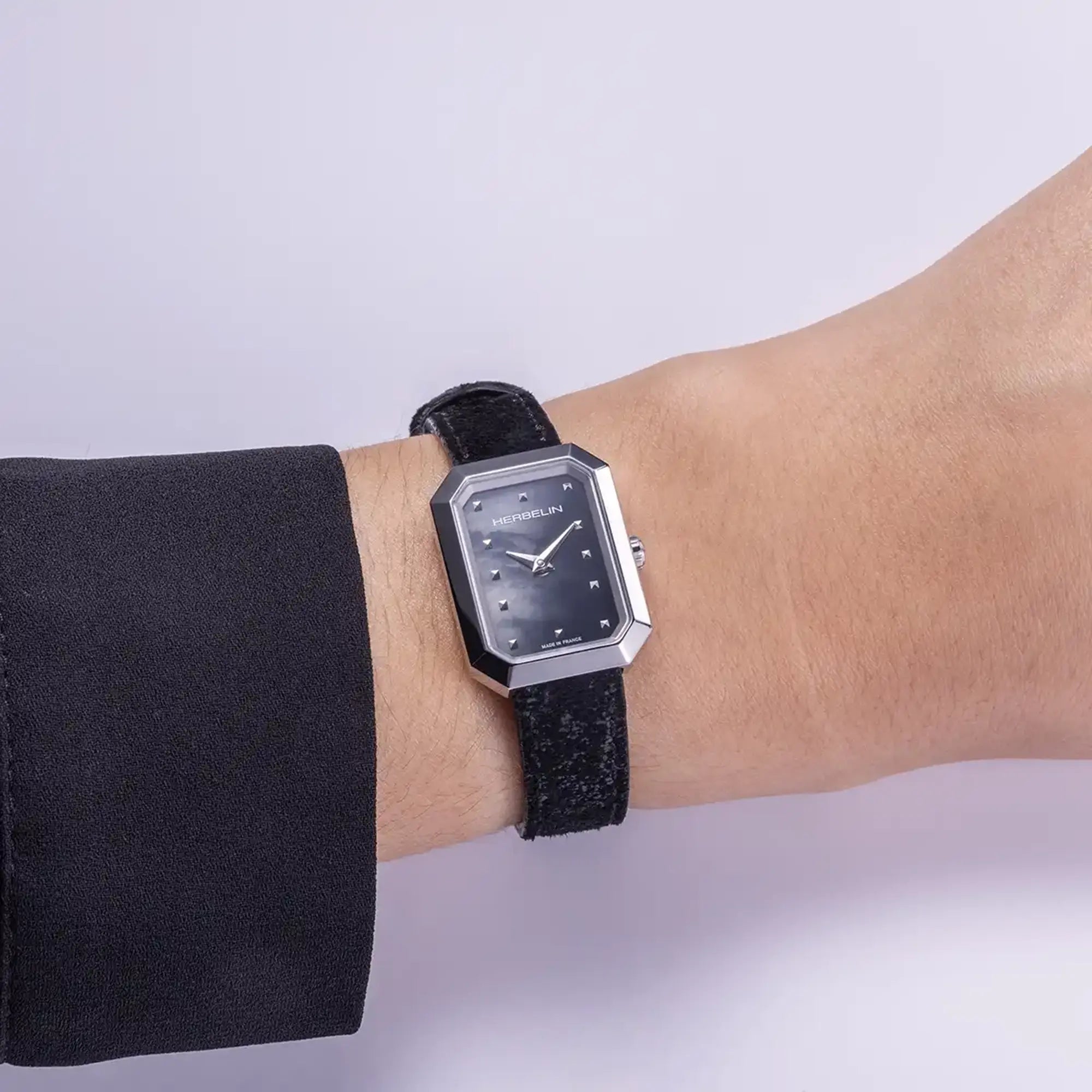 Au poignet féminin, cadran nacre noire et bracelet cuir visibles