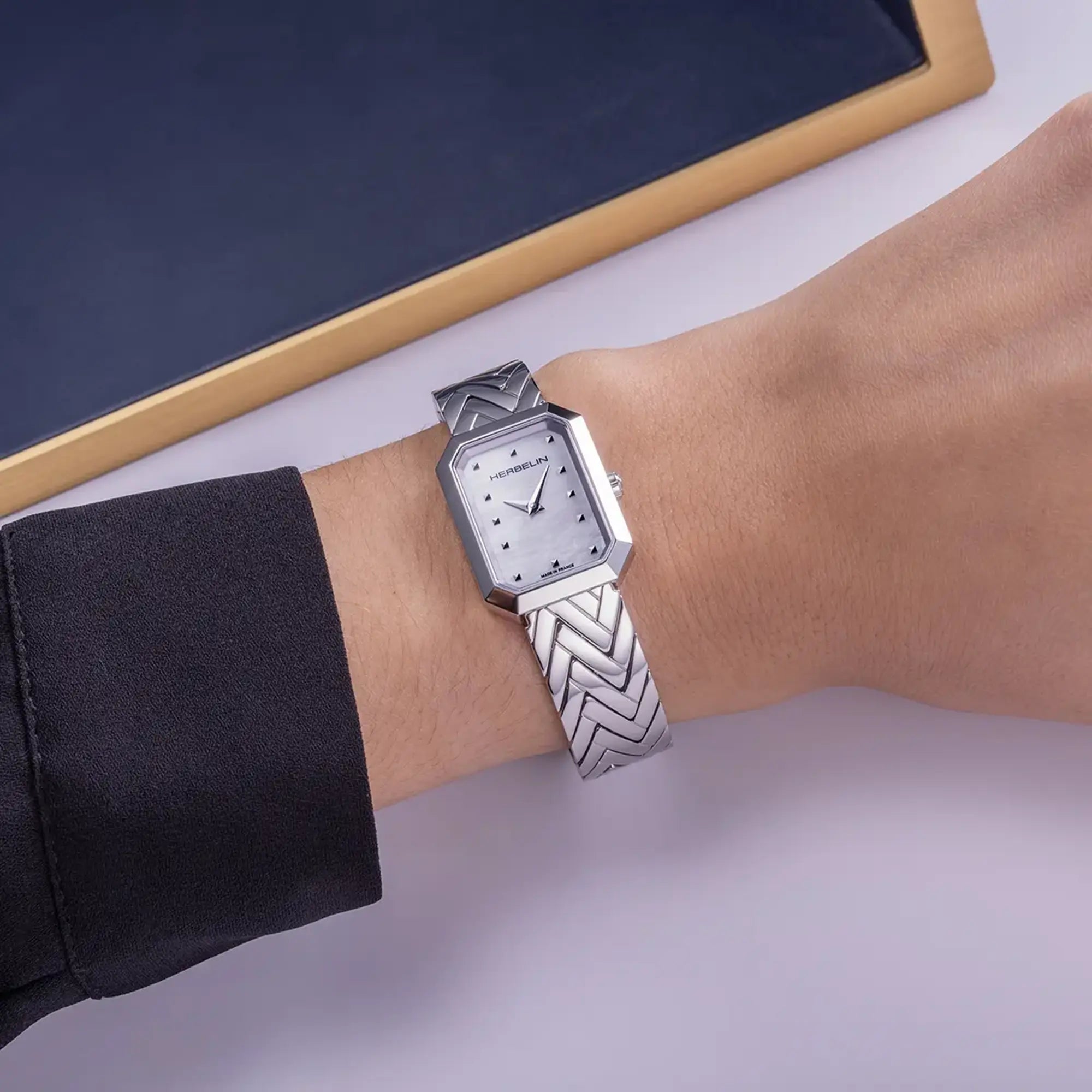 Au poignet féminin, cadran nacre blanche et bracelet acier visibles