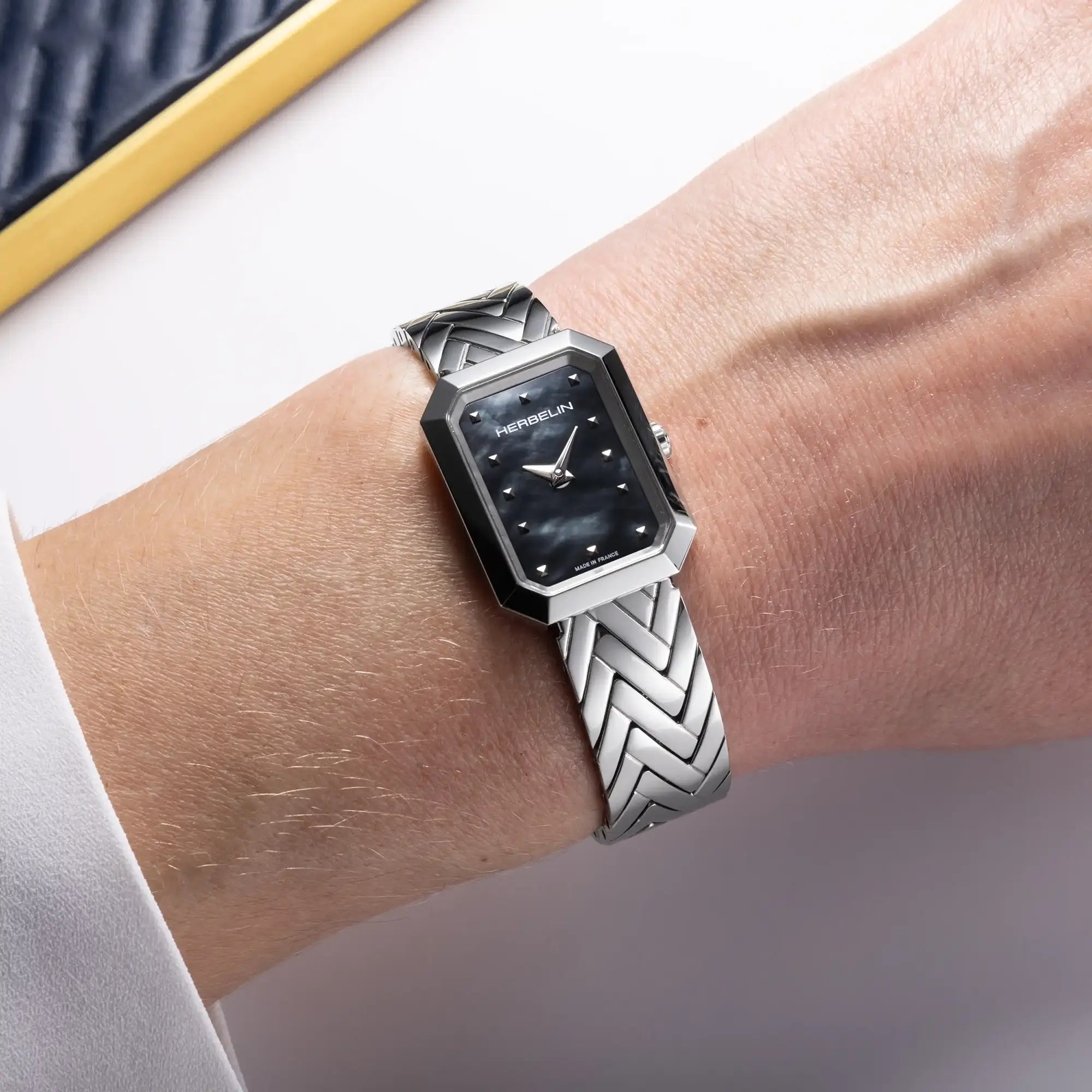 Au poignet féminin, cadran nacre noire et bracelet acier visibles