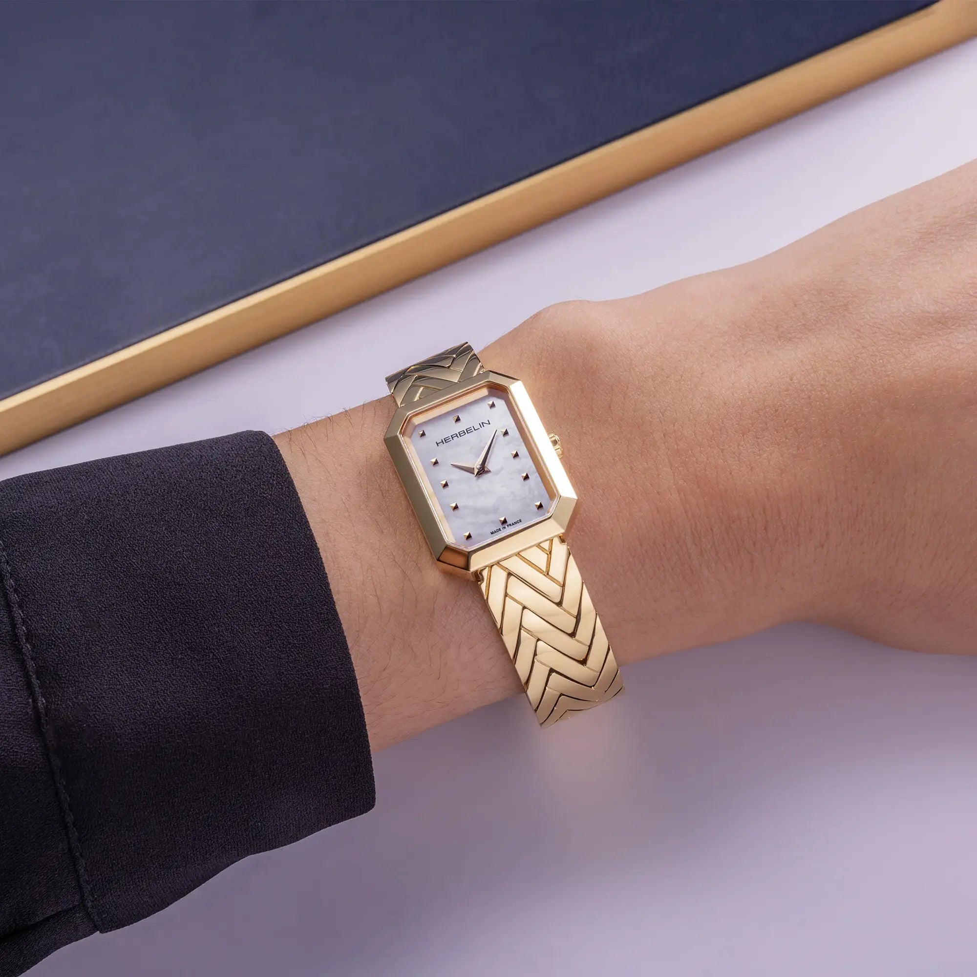 Au poignet féminin, cadran nacre blanche et bracelet acier bicolore visibles