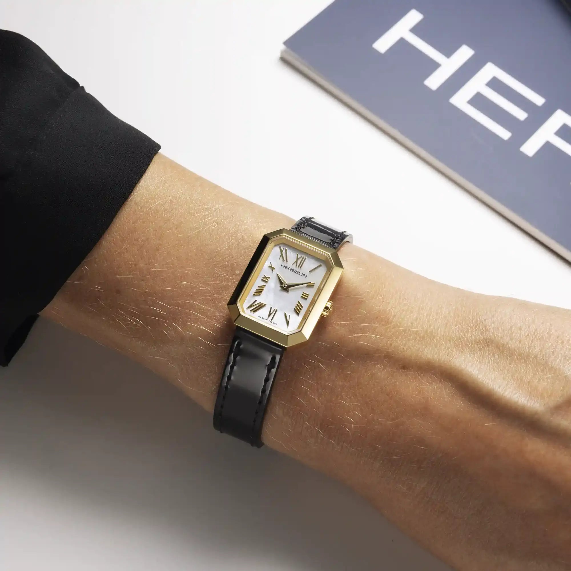 Au poignet féminin, cadran nacre blanche et bracelet cuir visibles