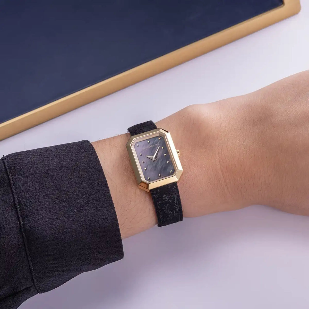 ⁣⁢En la muñeca femenina, esfera nácar negro y brazalete de piel visibles⁤⁣