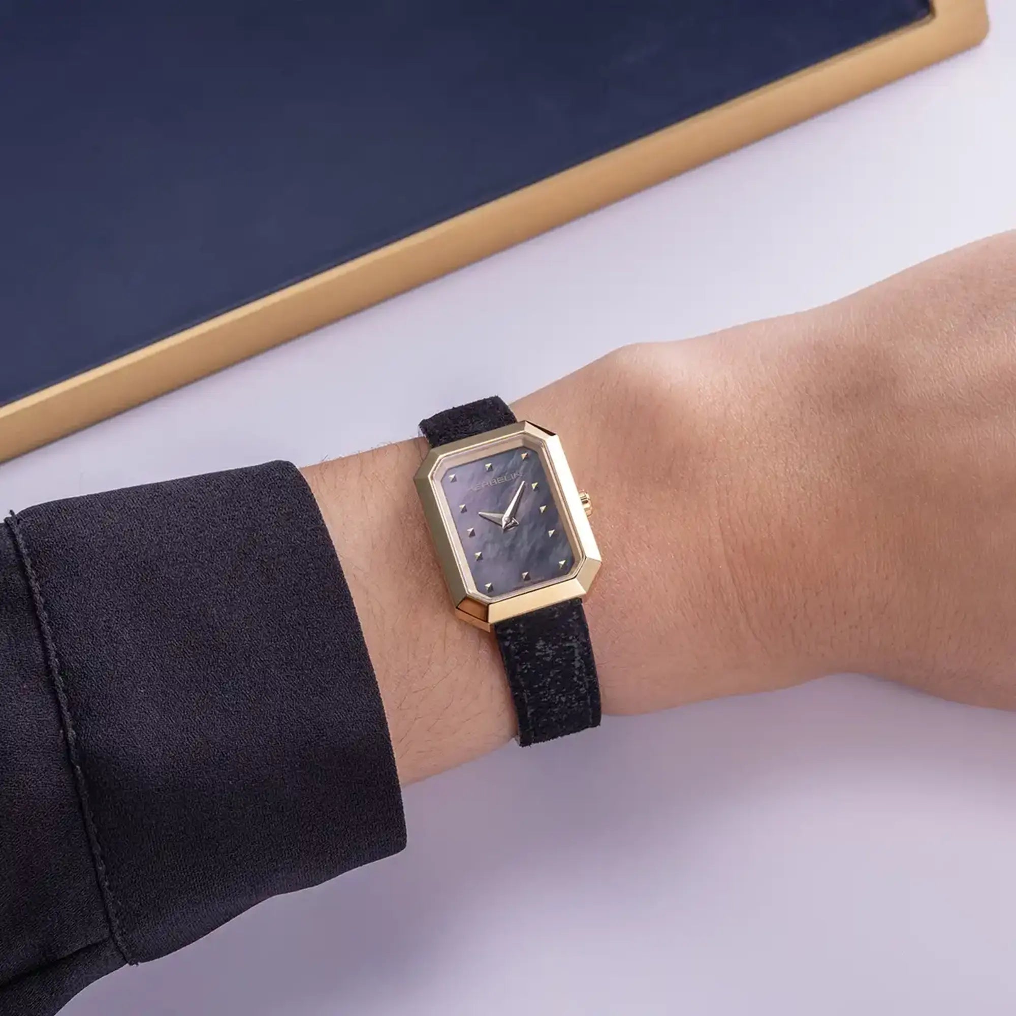 Au poignet féminin, cadran nacre noire et bracelet cuir visibles