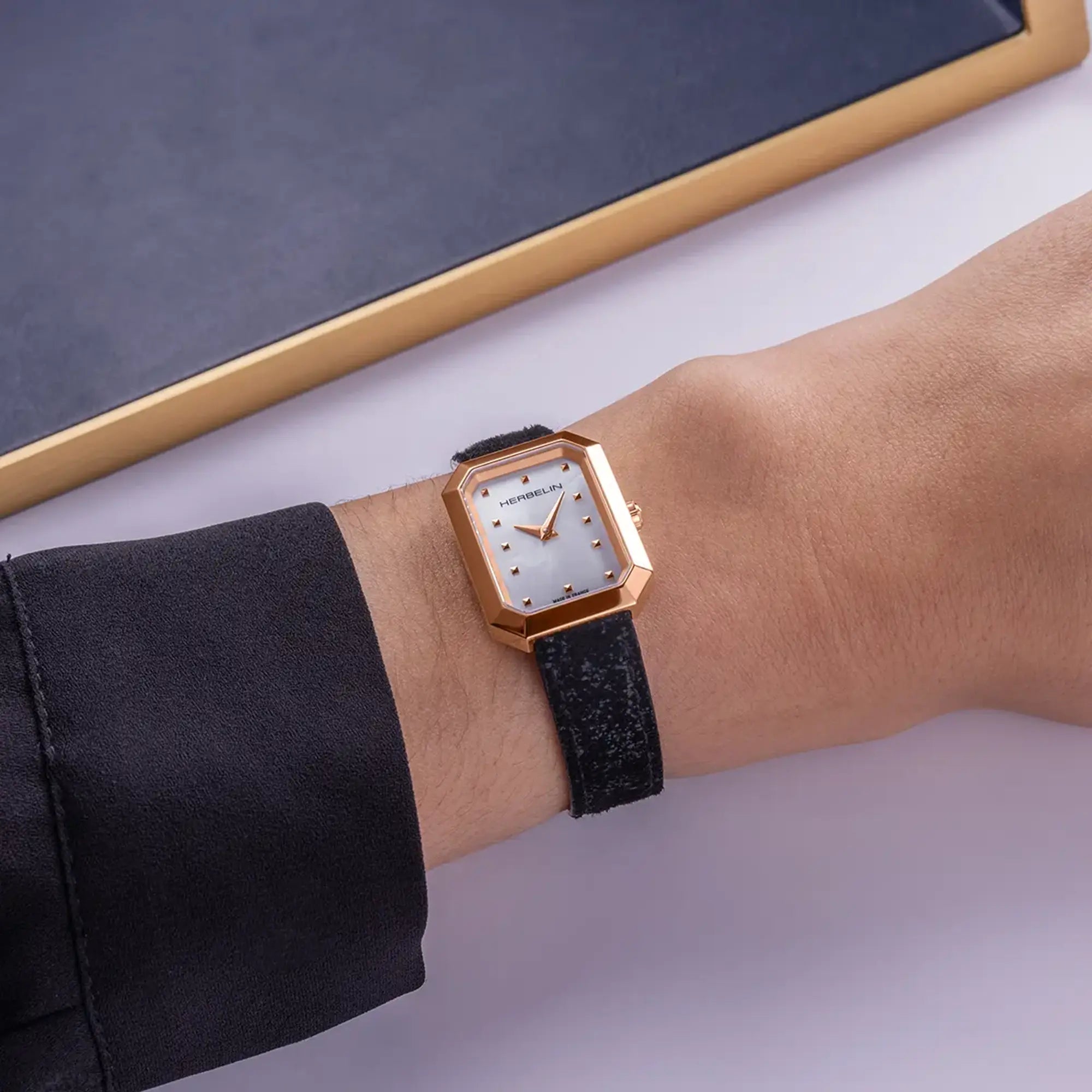 Au poignet féminin, cadran nacre blanche et bracelet cuir visibles