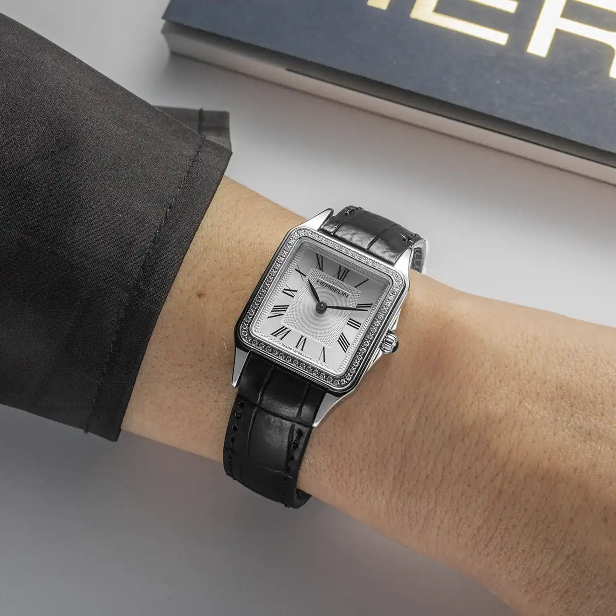 Au poignet féminin, cadran argent blanc et bracelet cuir visibles