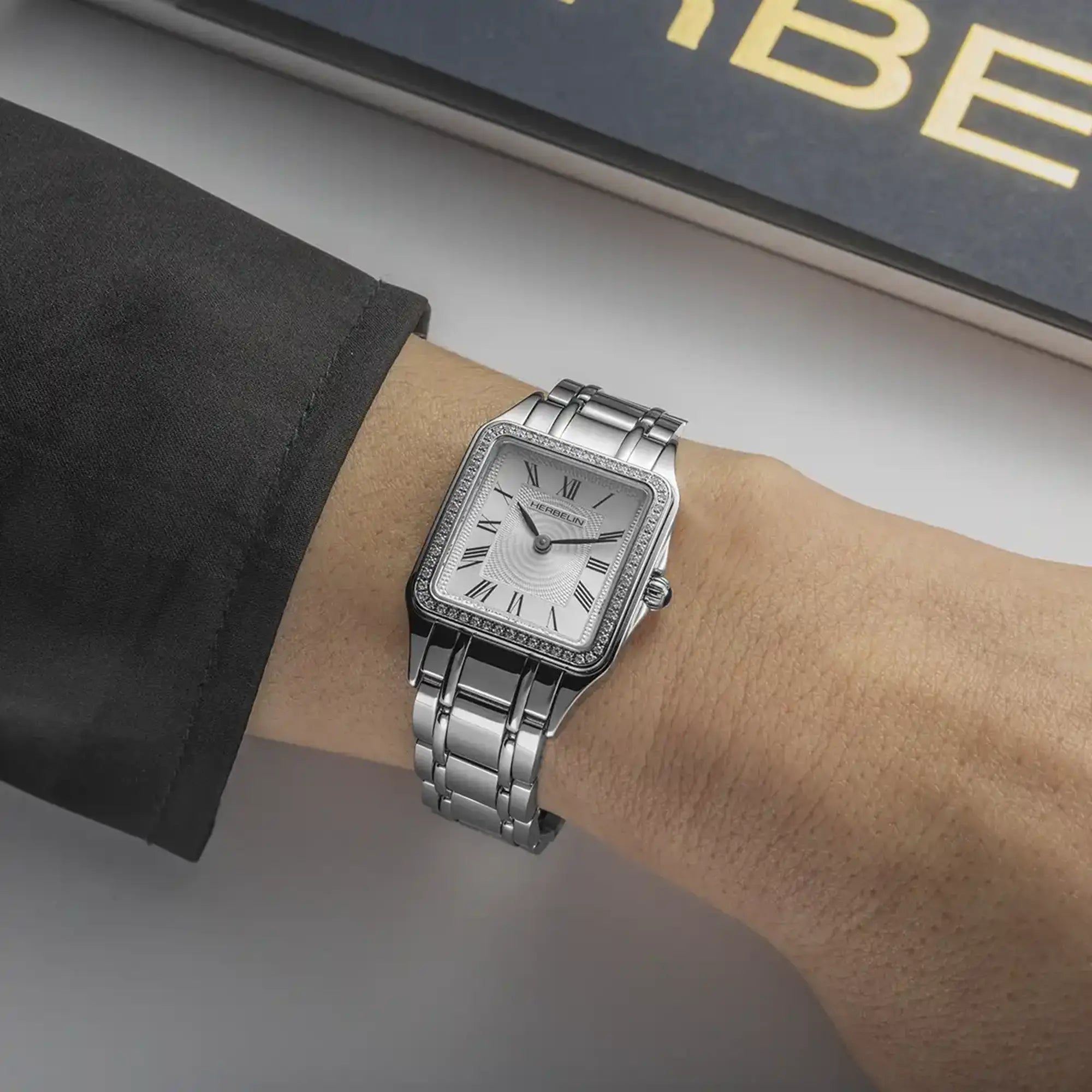 Au poignet féminin, cadran argent blanc et bracelet acier visibles