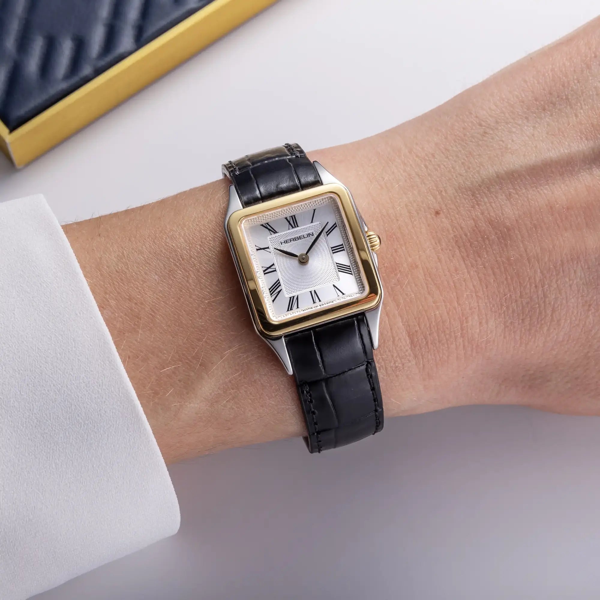 Au poignet féminin, cadran argent guilloché et bracelet cuir visibles