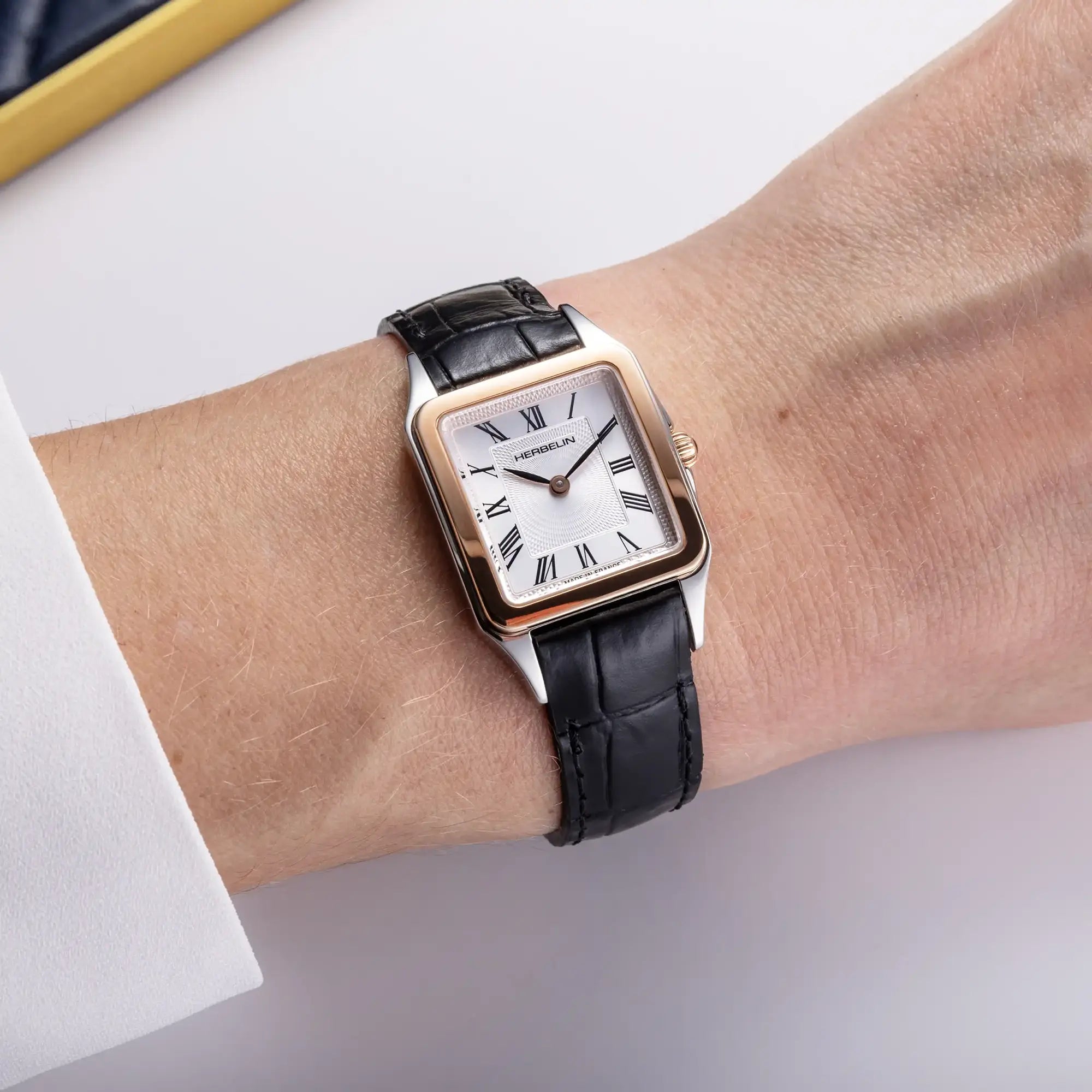 Au poignet féminin, cadran argent guilloché et bracelet cuir visibles
