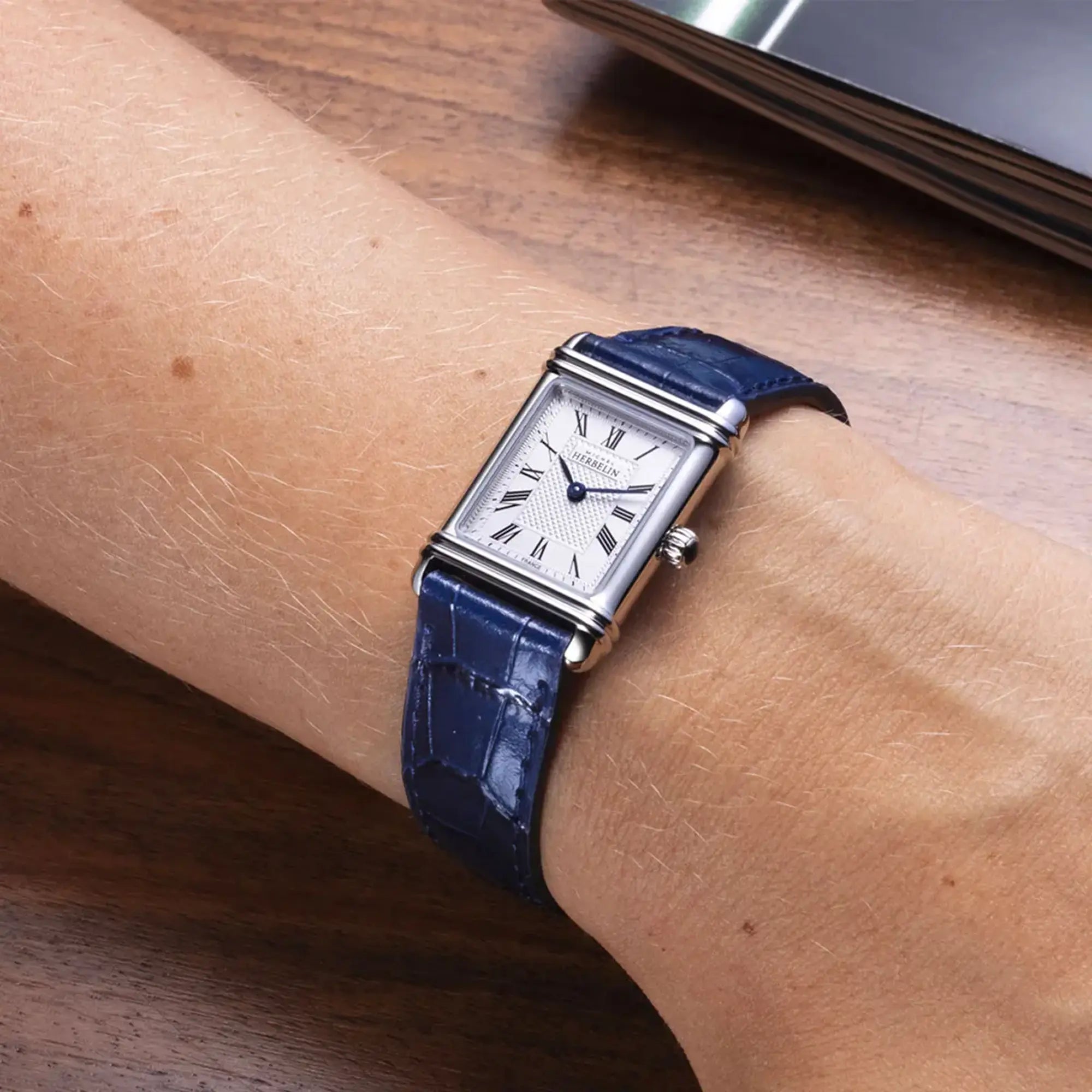 Au poignet féminin, cadran argent guilloché et bracelet cuir visibles