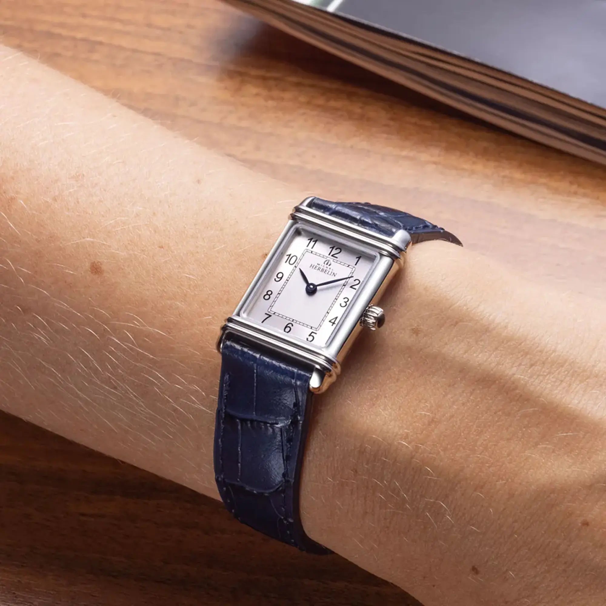 Au poignet féminin, cadran argent guilloché et bracelet cuir visibles