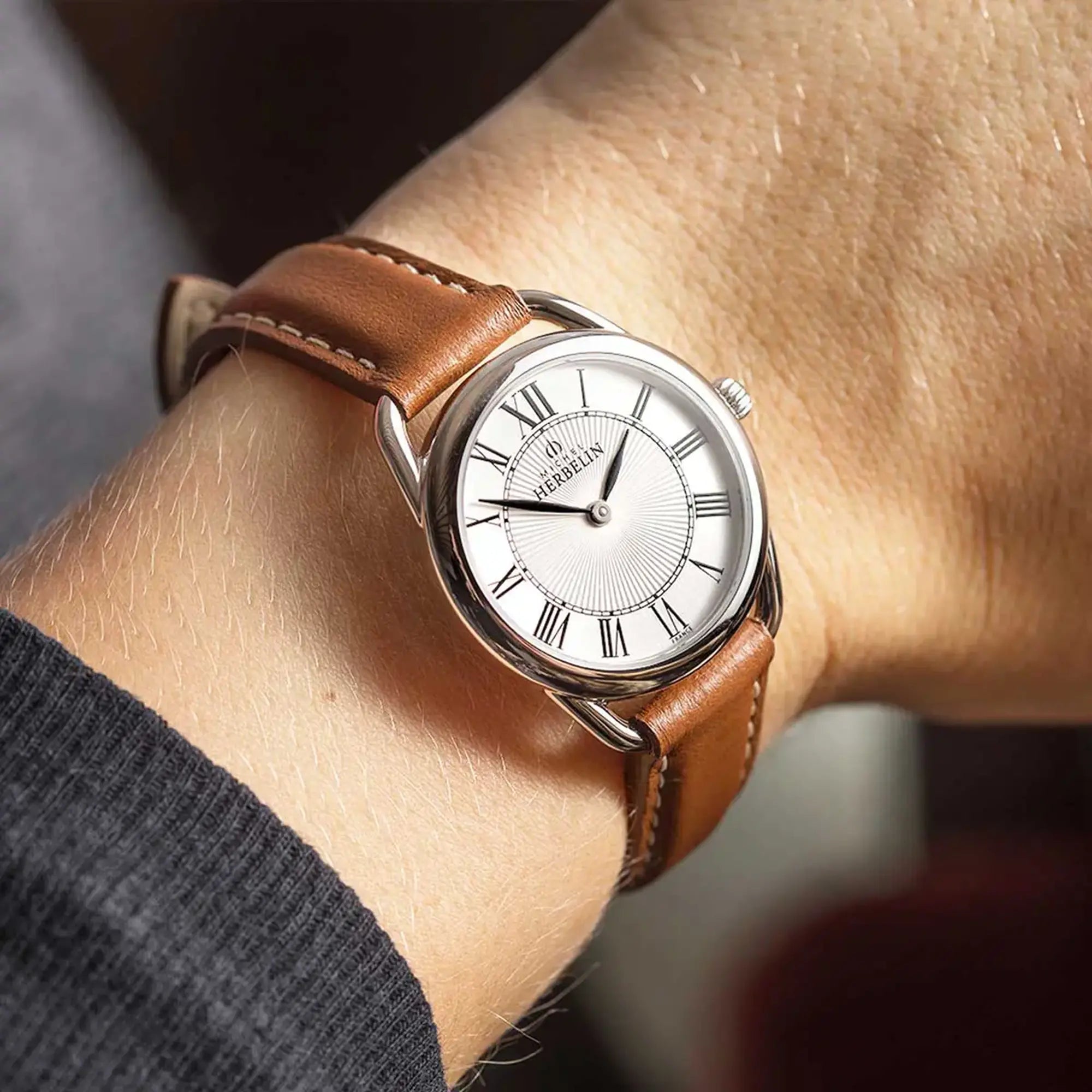 Au poignet féminin, cadran argent guilloché et bracelet cuir visibles