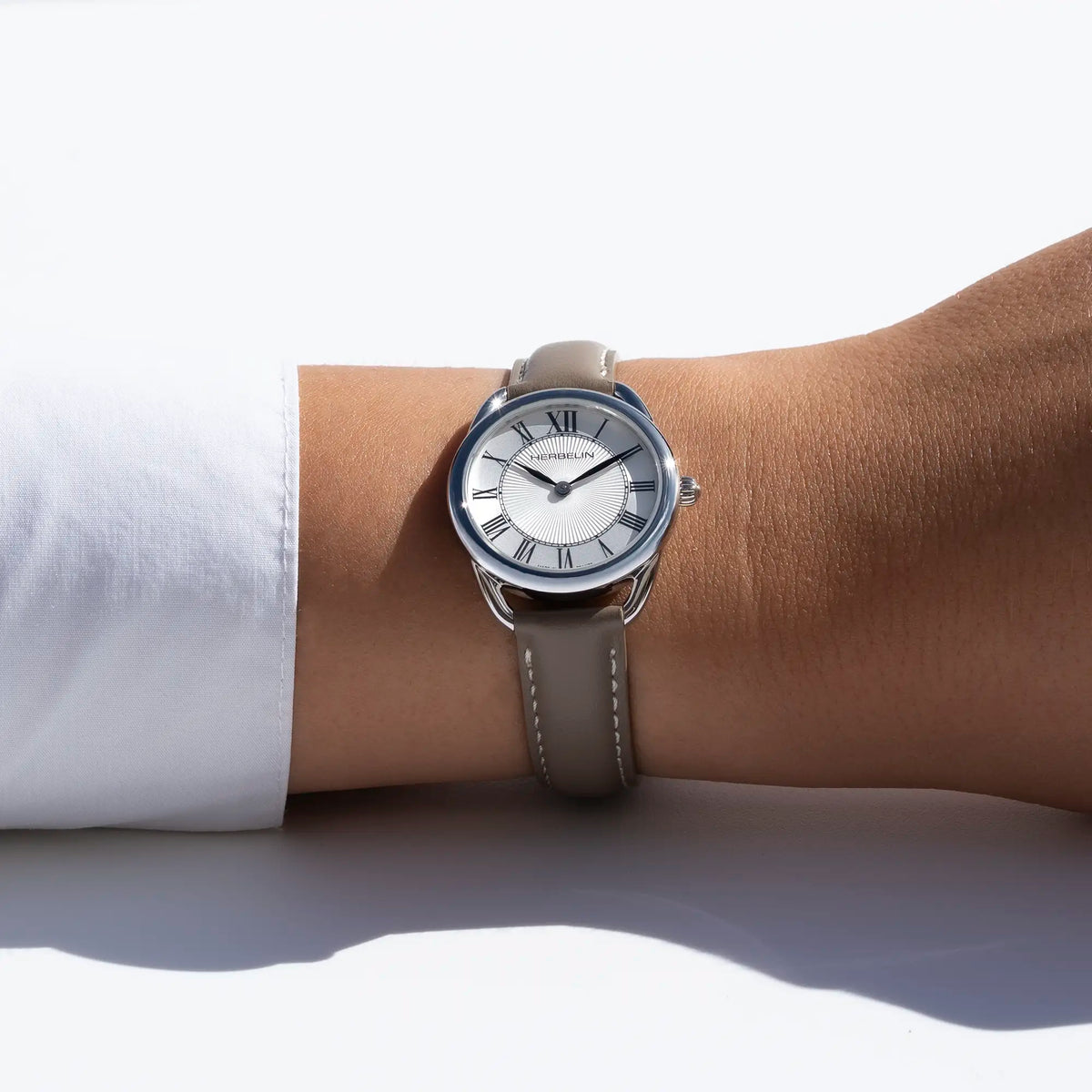 Autre vue au poignet féminin, cadran argent blanc guilloché et bracelet cuir visibles