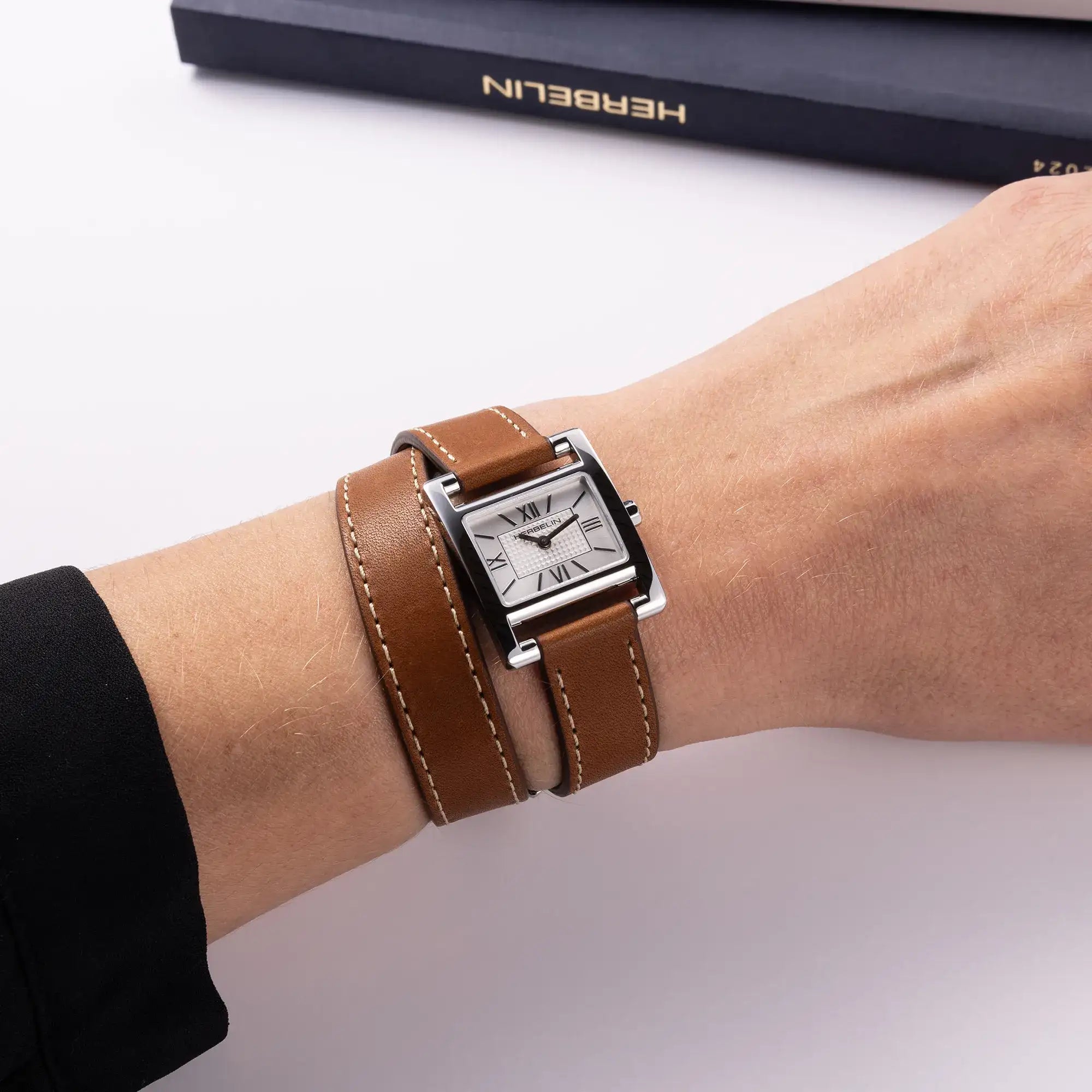 Au poignet féminin, cadran argent guilloché et bracelet cuir visibles