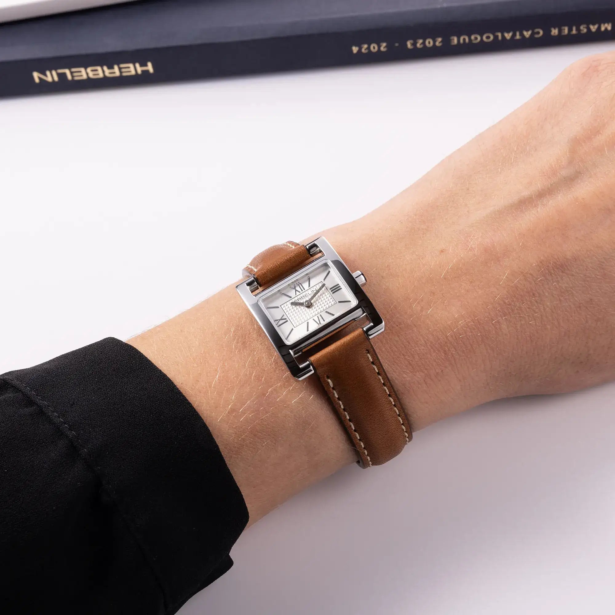 Au poignet féminin, cadran argent guilloché et bracelet cuir visibles