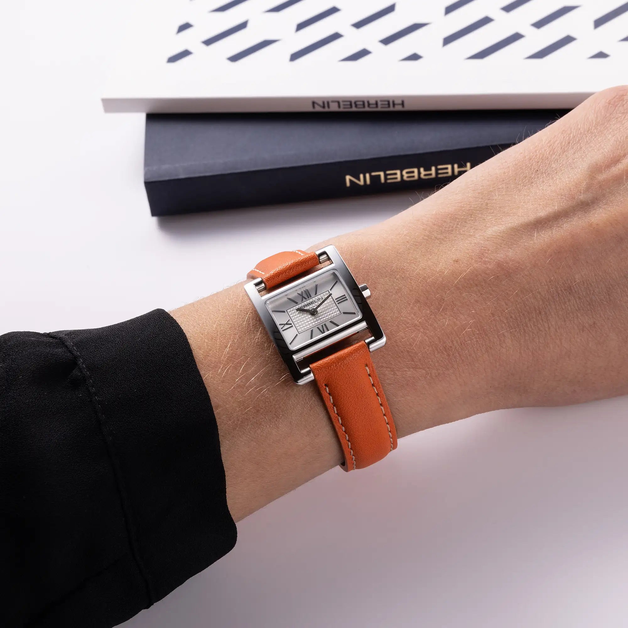 Au poignet féminin, cadran argent guilloché et bracelet cuir visibles
