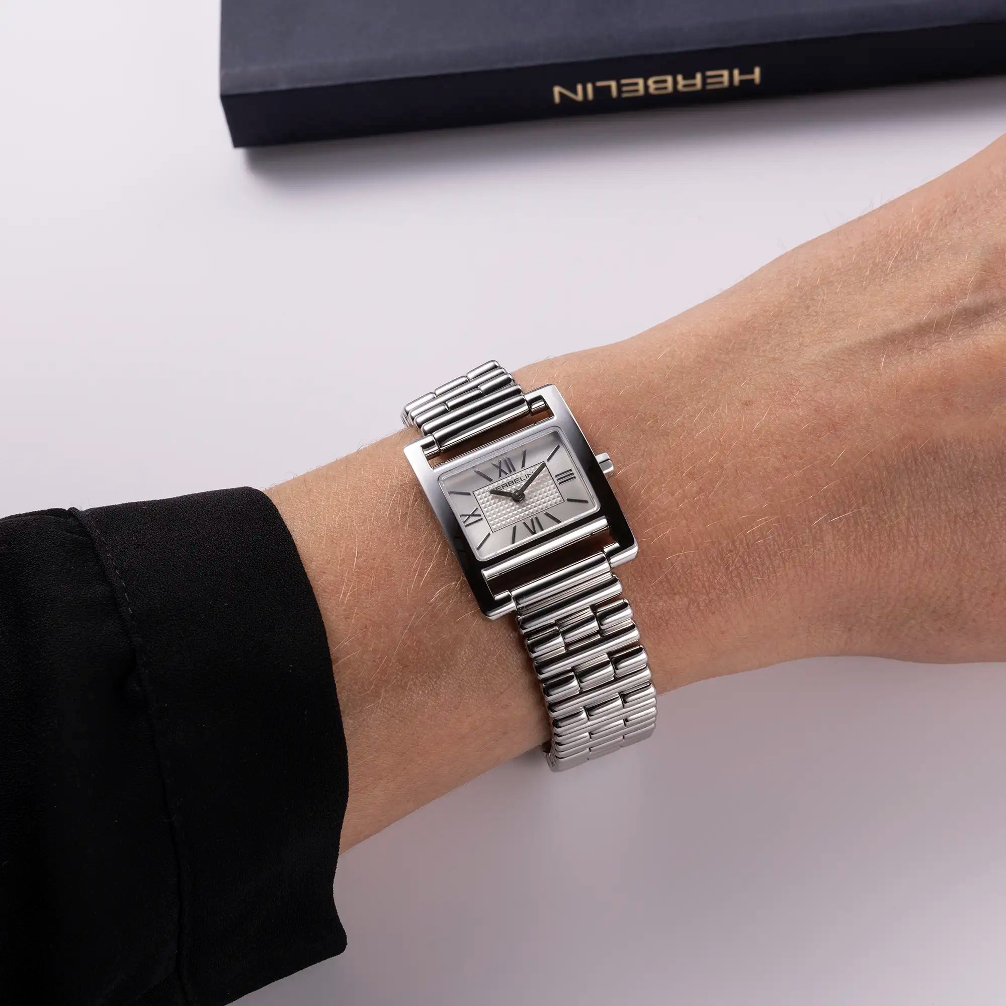 Au poignet féminin, cadran argent guilloché et bracelet acier visibles