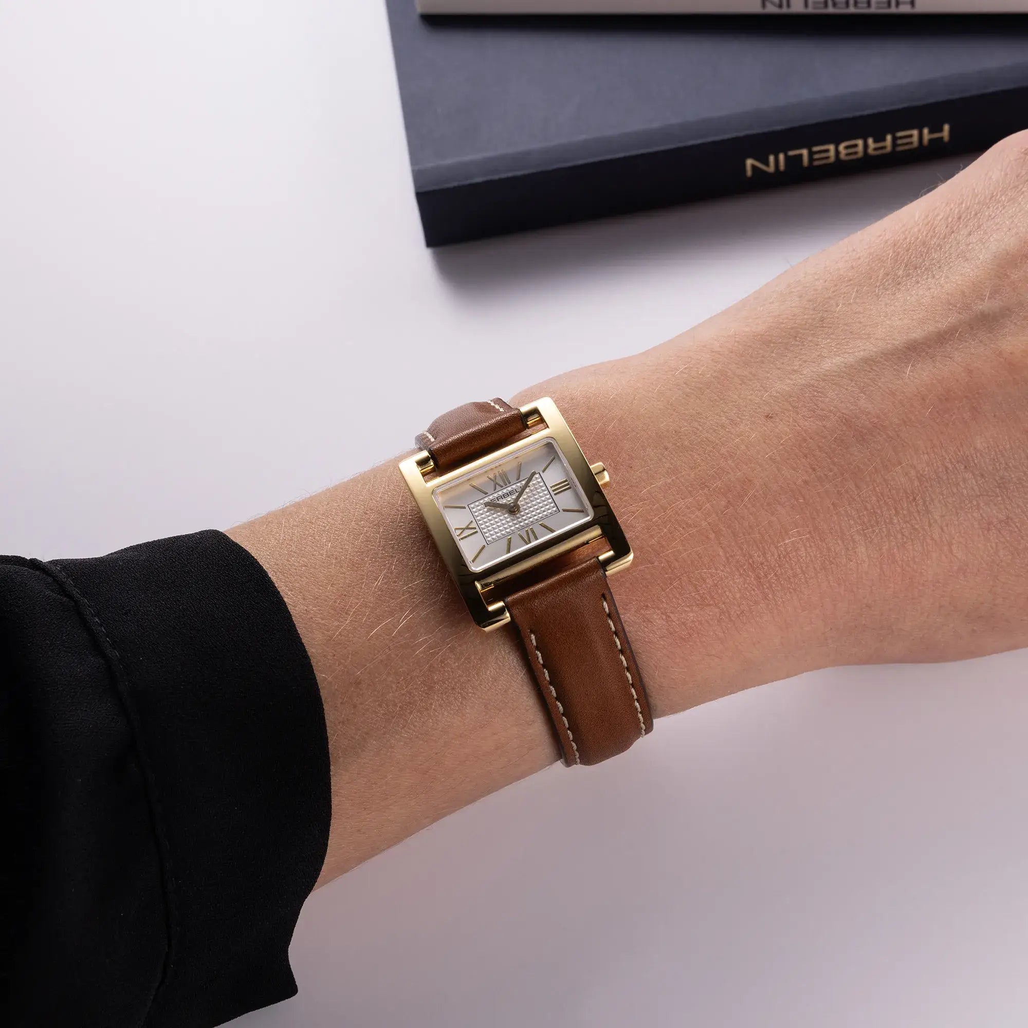 Au poignet féminin, cadran argent guilloché et bracelet cuir visibles