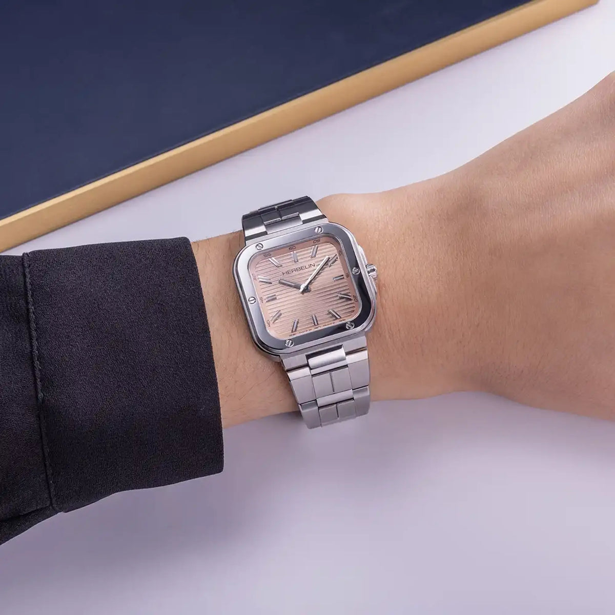 ⁣⁢En la muñeca femenina, esfera champagne rosado y brazalete de acero visibles⁤⁣
