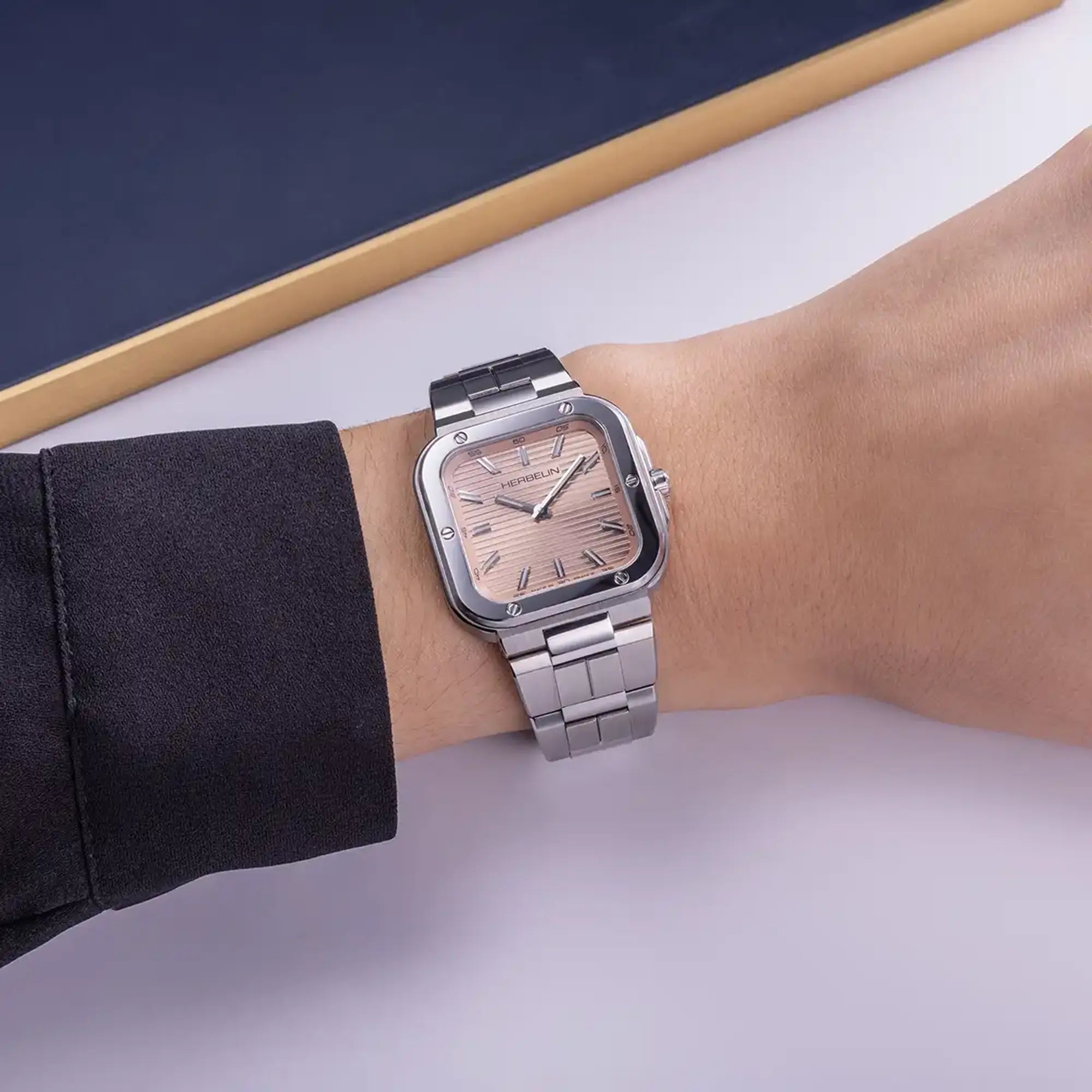 Au poignet féminin, cadran champagne rosé et bracelet acier visibles