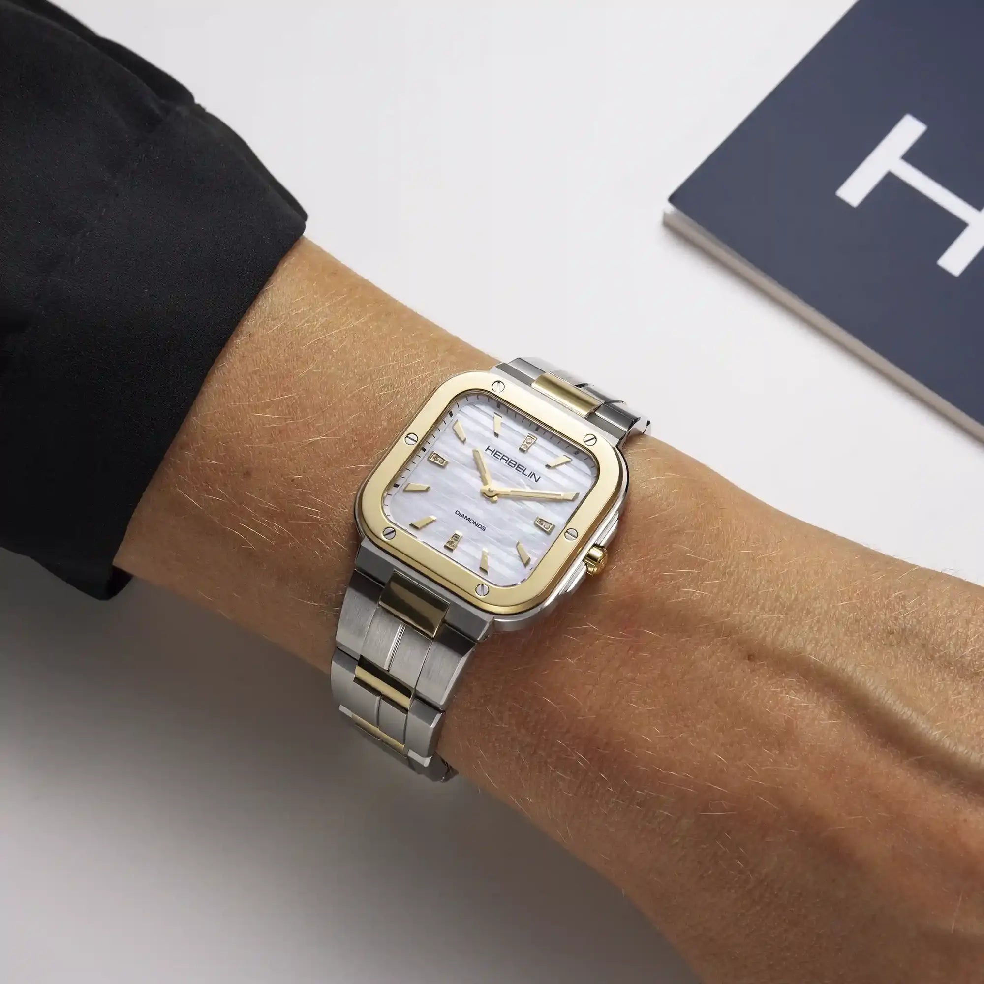 Au poignet féminin, cadran nacre blanche et bracelet acier bicolore visibles