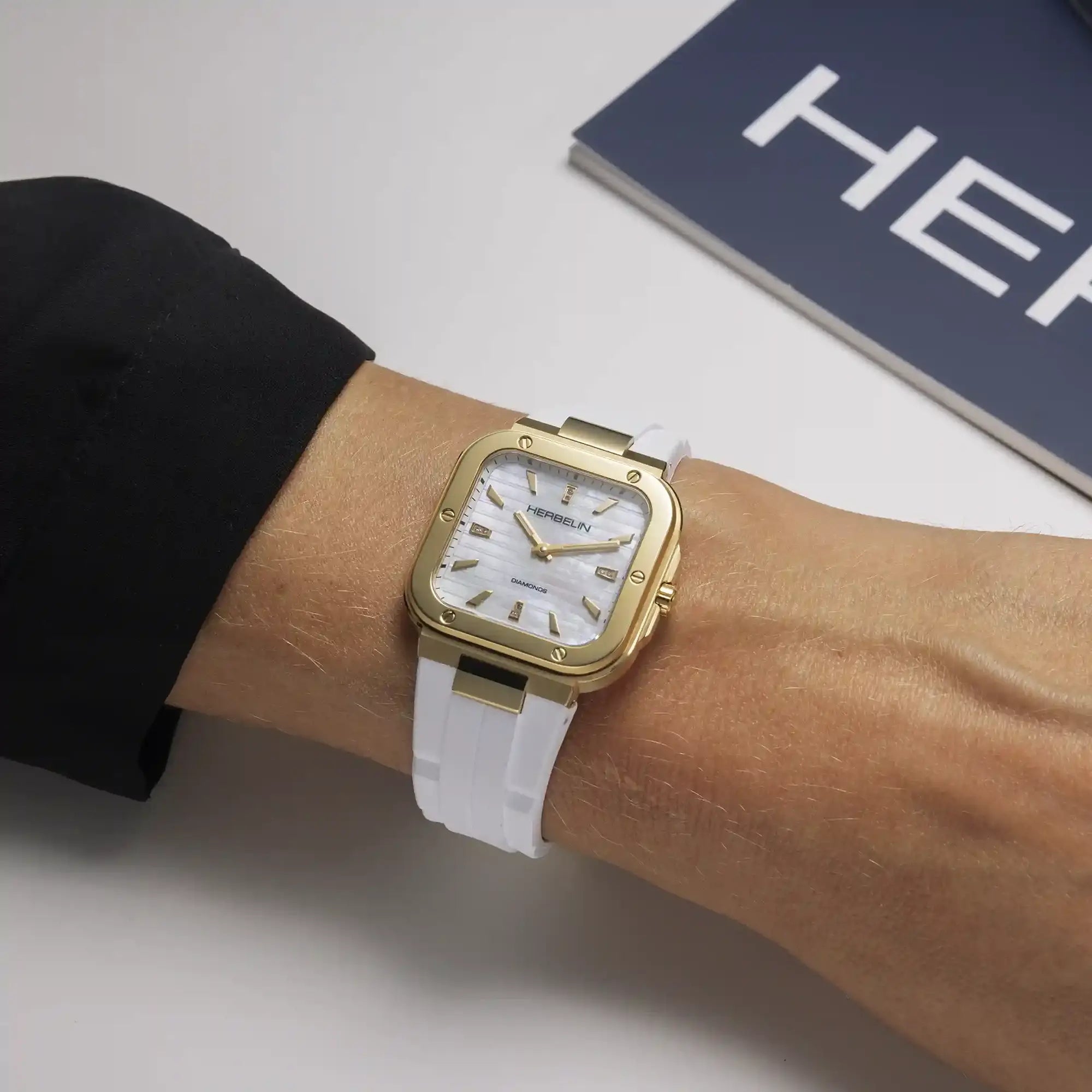 Au poignet féminin, cadran nacre blanche et bracelet caoutchouc visibles