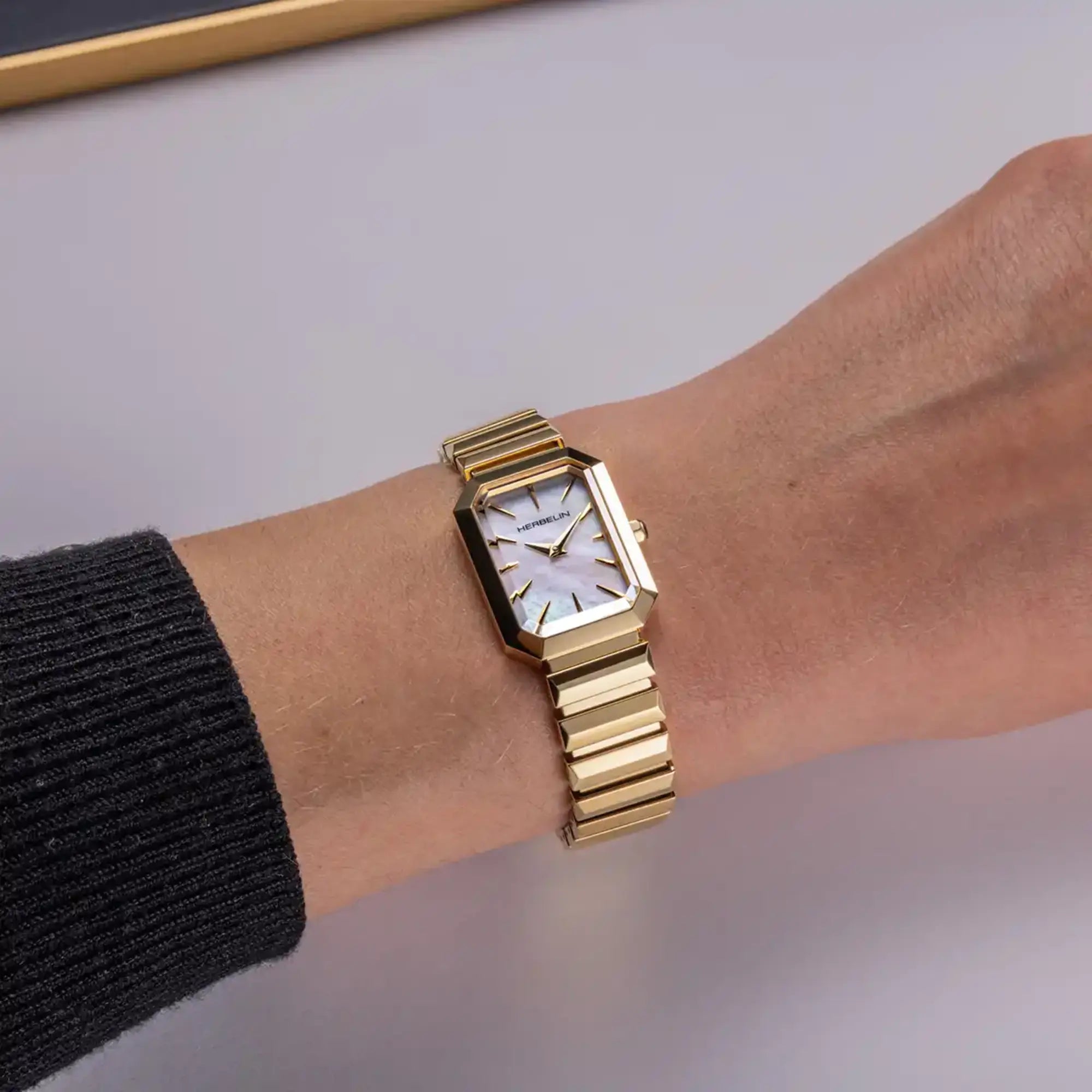 Au poignet féminin, cadran nacre blanche et bracelet acier bicolore visibles