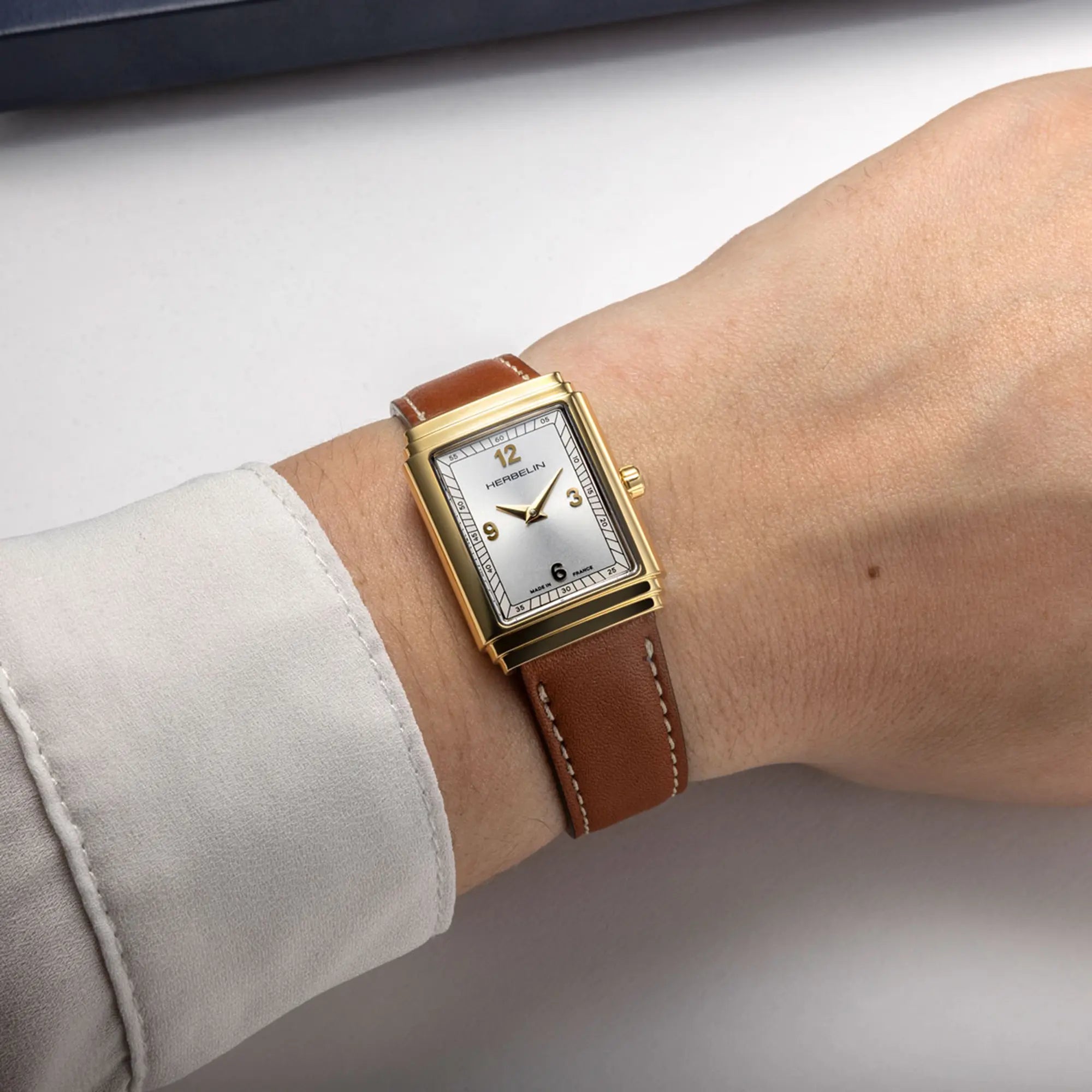 Au poignet féminin, cadran argent et bracelet cuir visibles