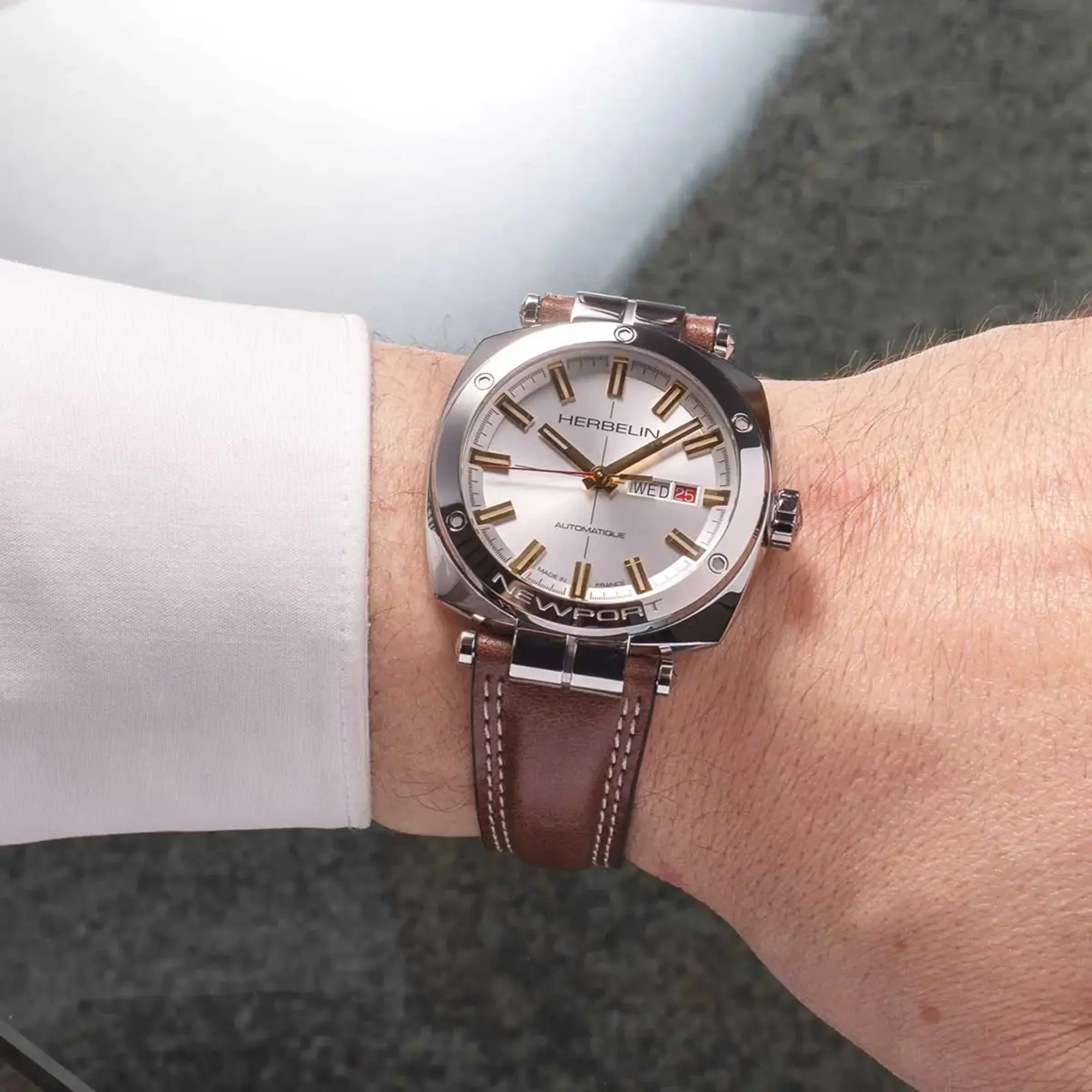 Au poignet masculin, cadran argent et bracelet cuir visibles