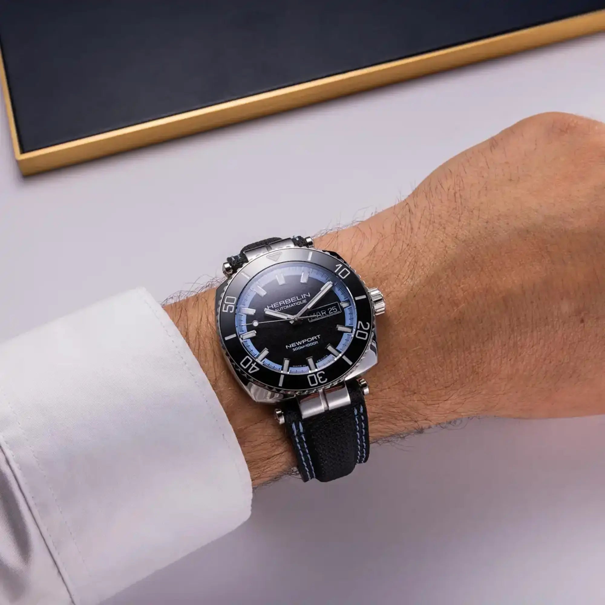 Au poignet masculin, cadran noir mat et bracelet textile visibles