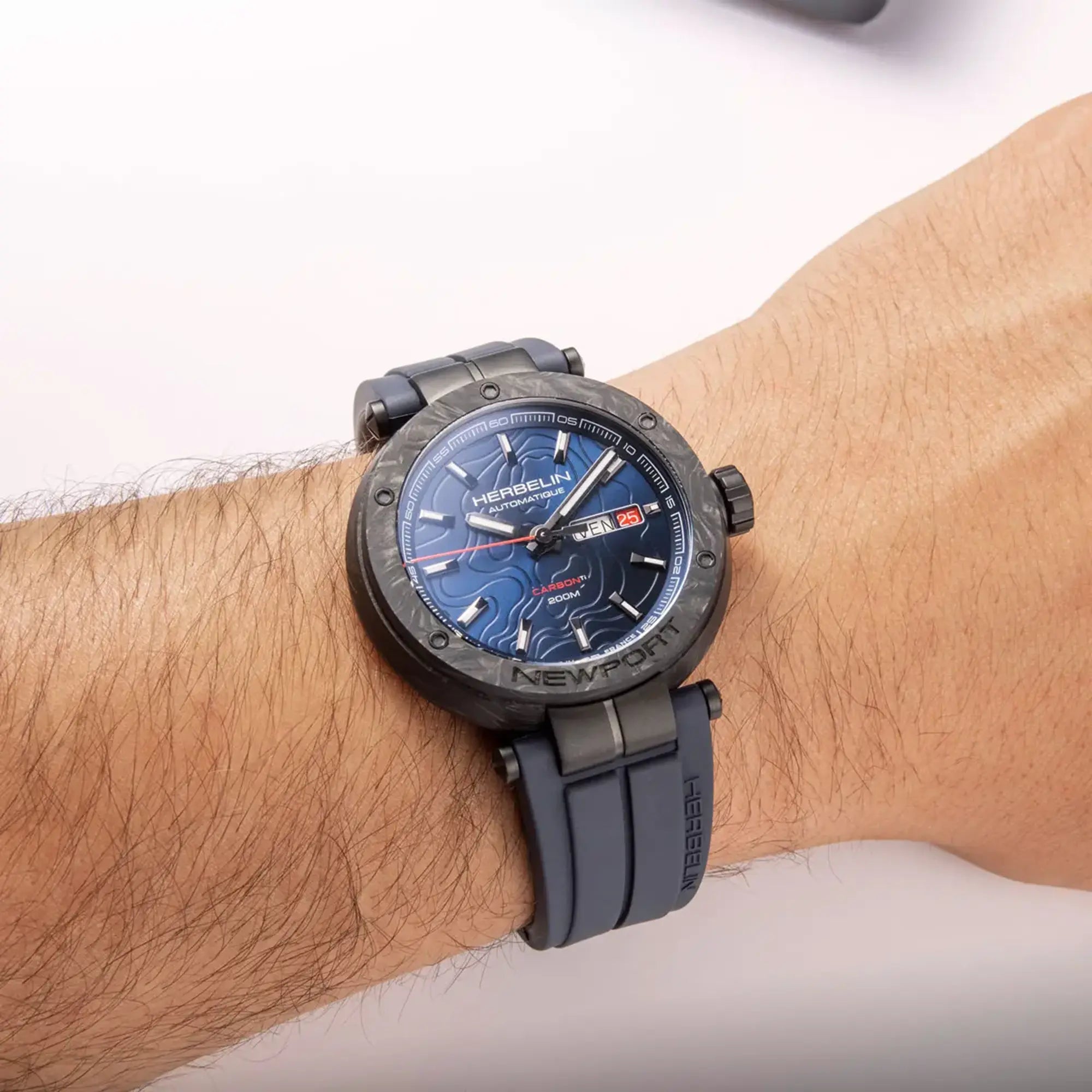 Au poignet masculin, cadran bleu et bracelet caoutchouc visibles