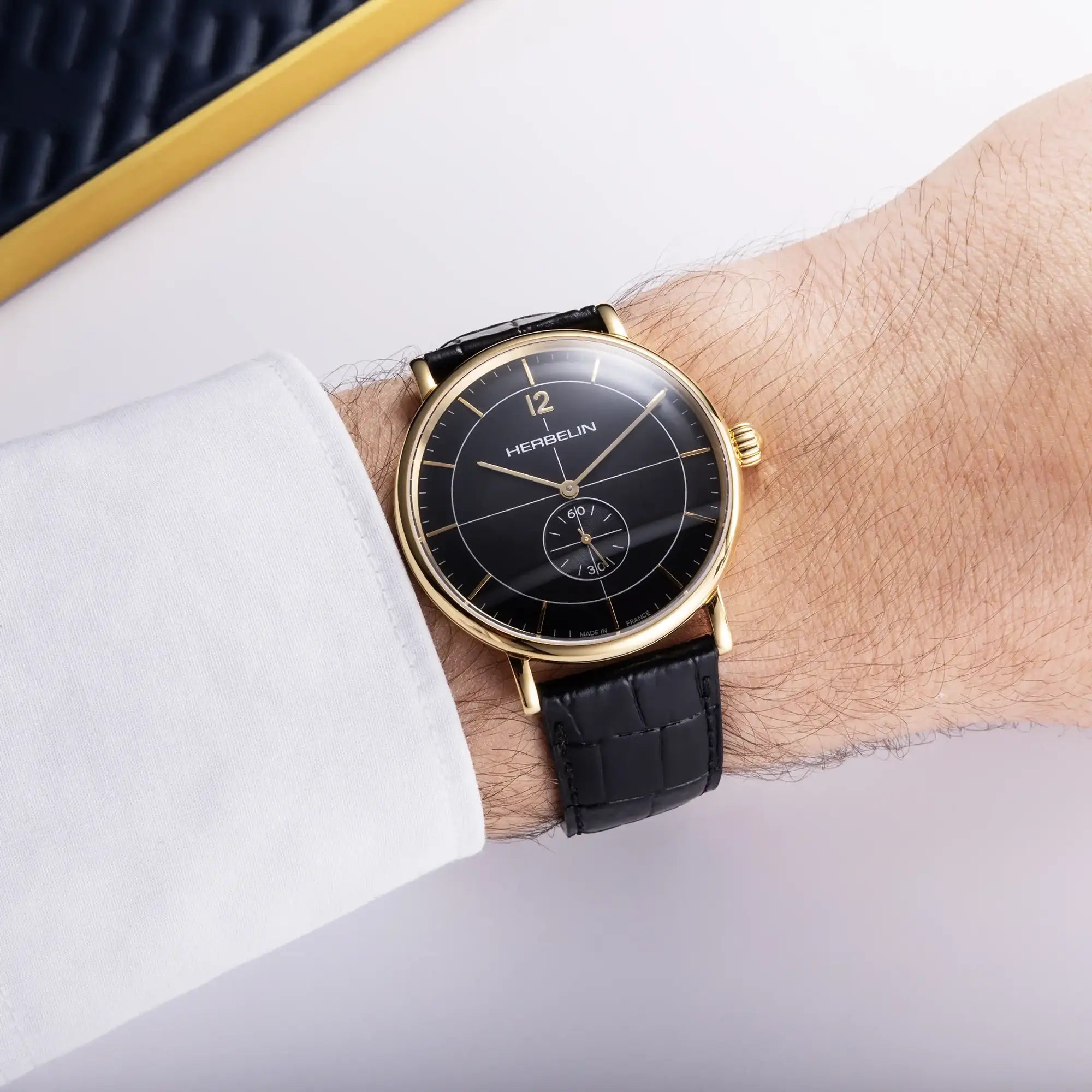 Au poignet masculin, cadran noir et bracelet cuir visibles