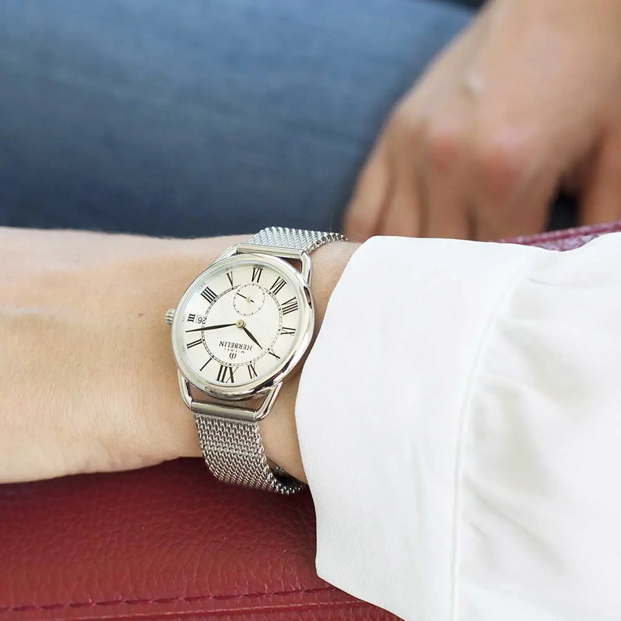 Au poignet féminin, cadran argent guilloché et bracelet acier visibles