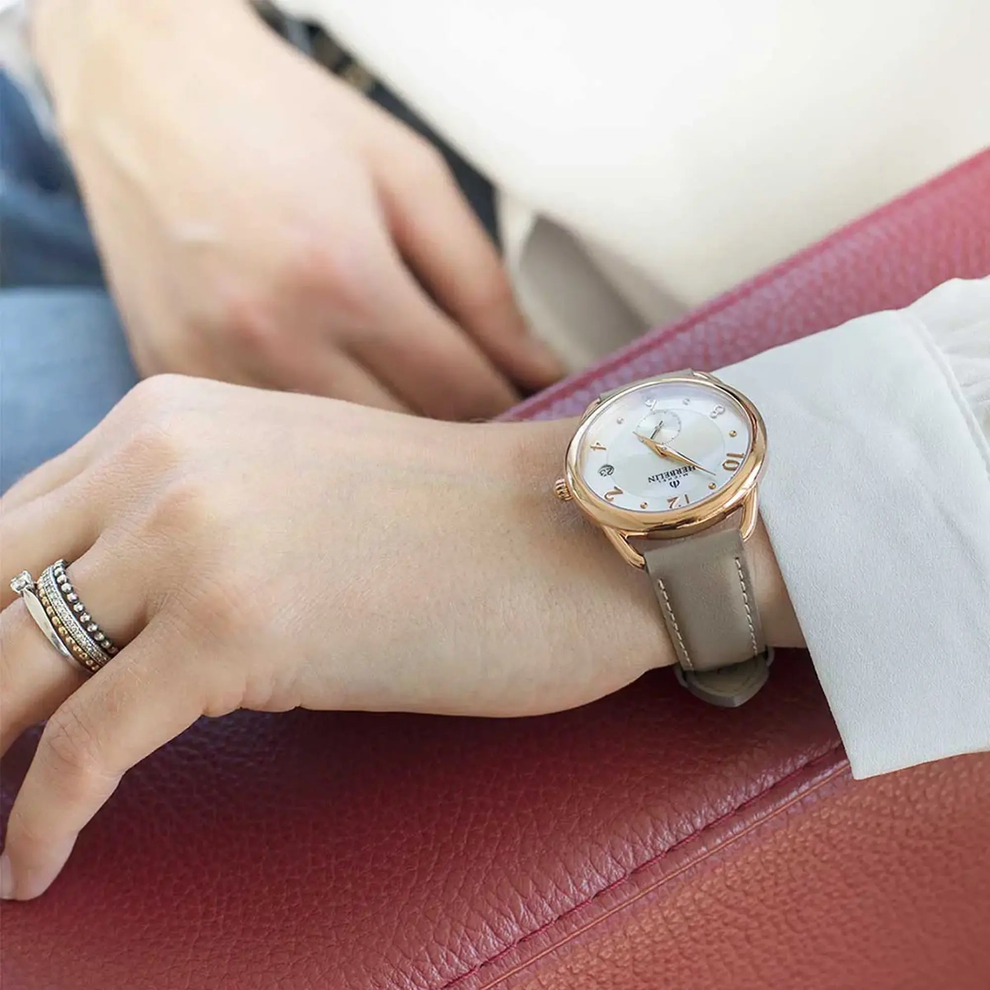 Au poignet féminin, cadran nacre blanche et bracelet cuir visibles