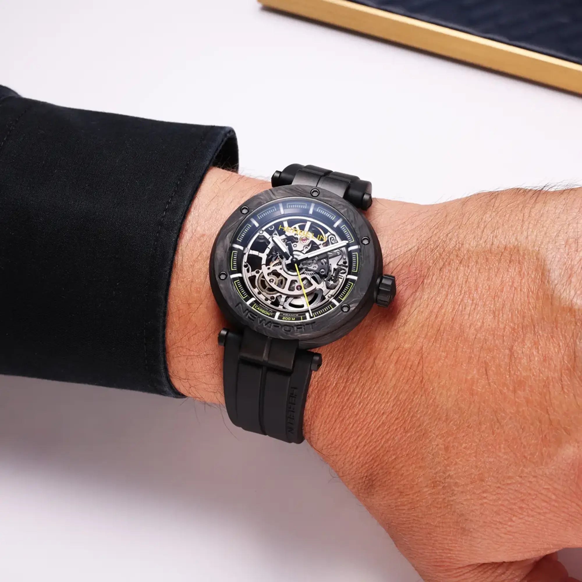 Au poignet masculin, cadran noir et bracelet caoutchouc visibles