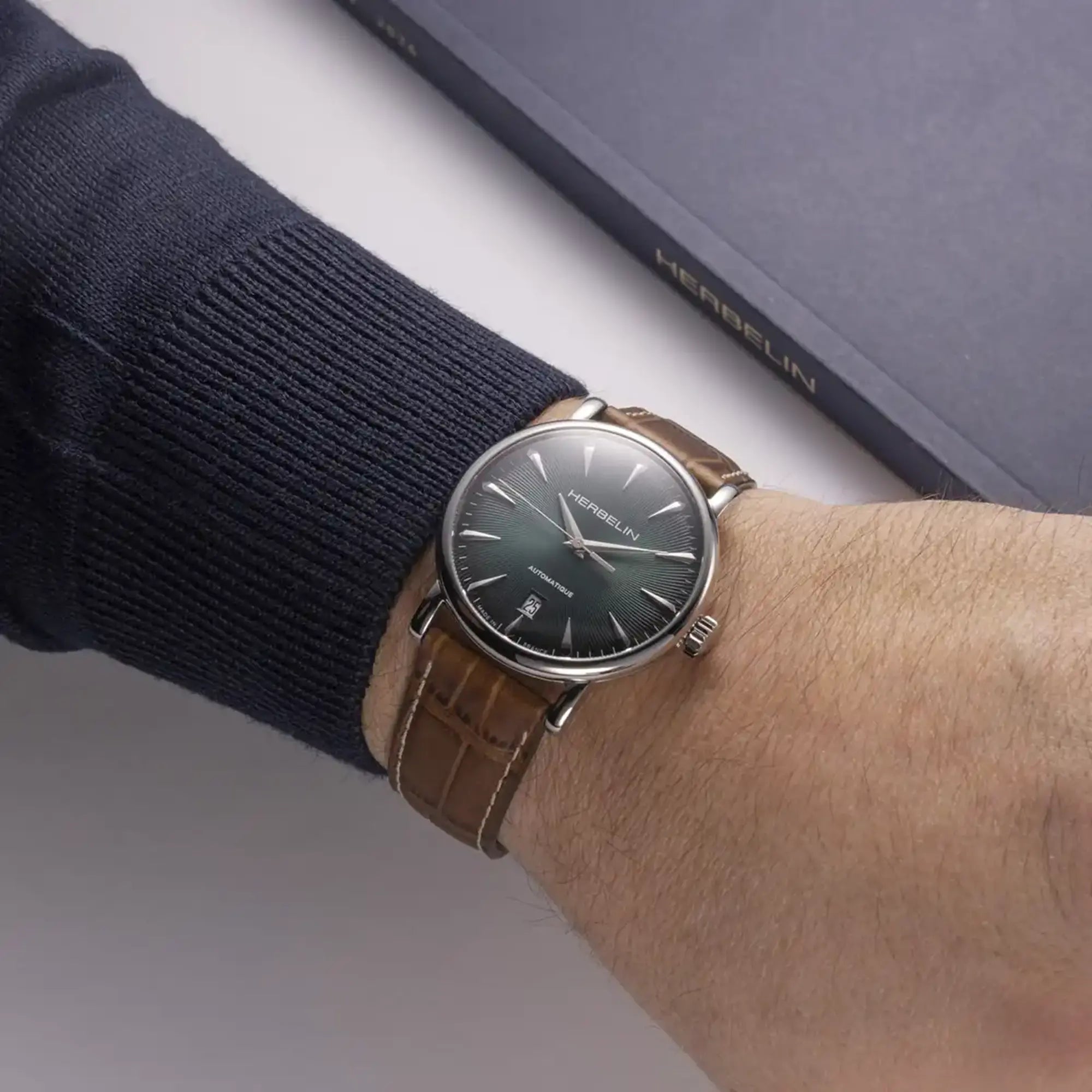 Au poignet masculin, cadran vert guilloché et bracelet cuir visibles