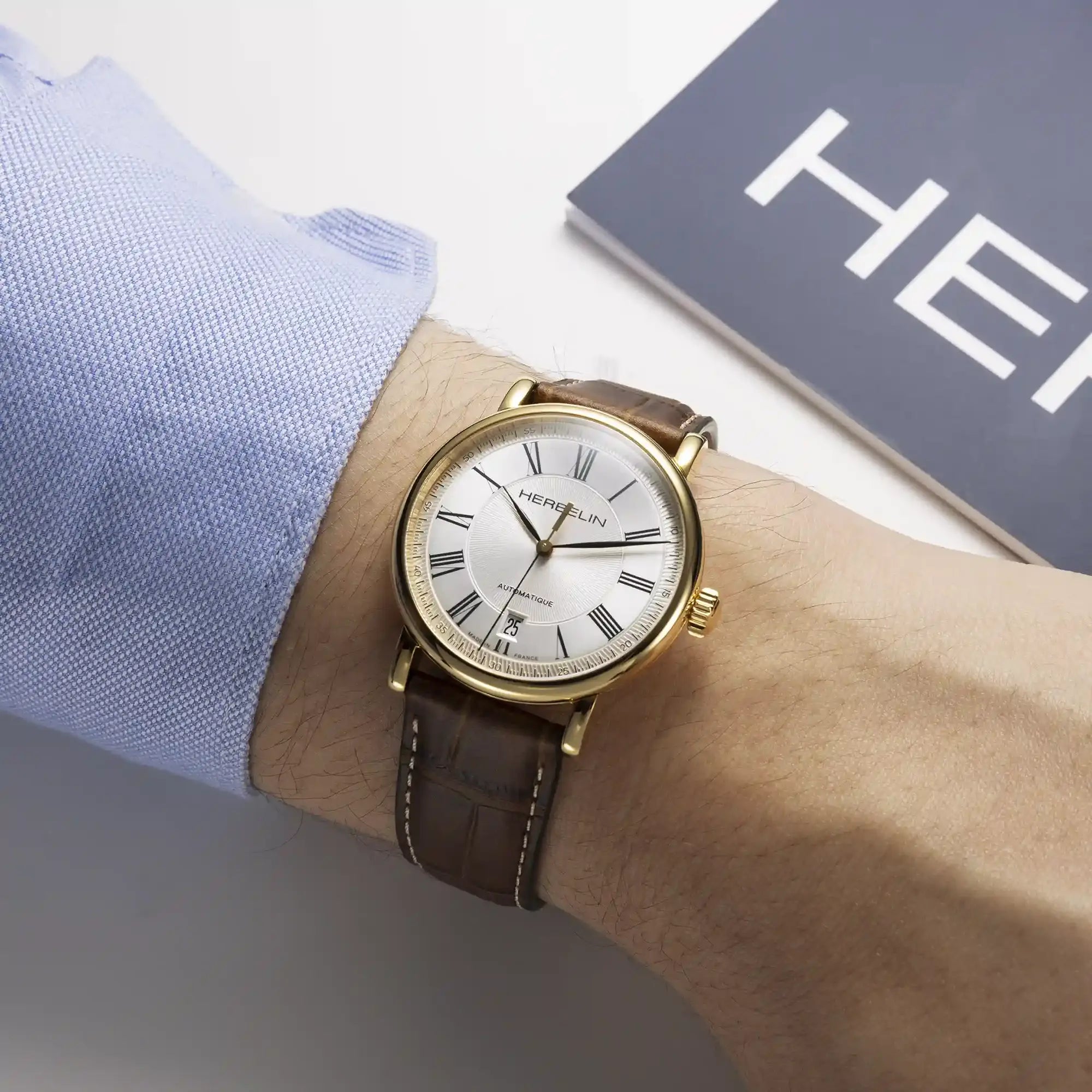 Au poignet masculin, cadran argent guilloché et bracelet cuir visibles