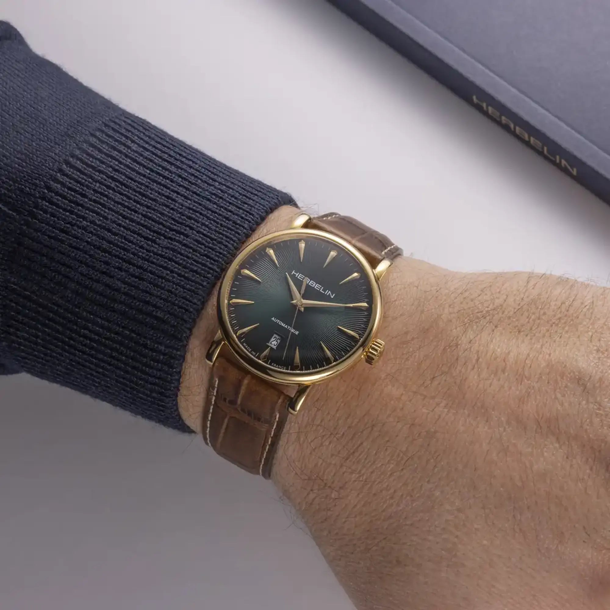 Au poignet masculin, cadran vert guilloché et bracelet cuir visibles