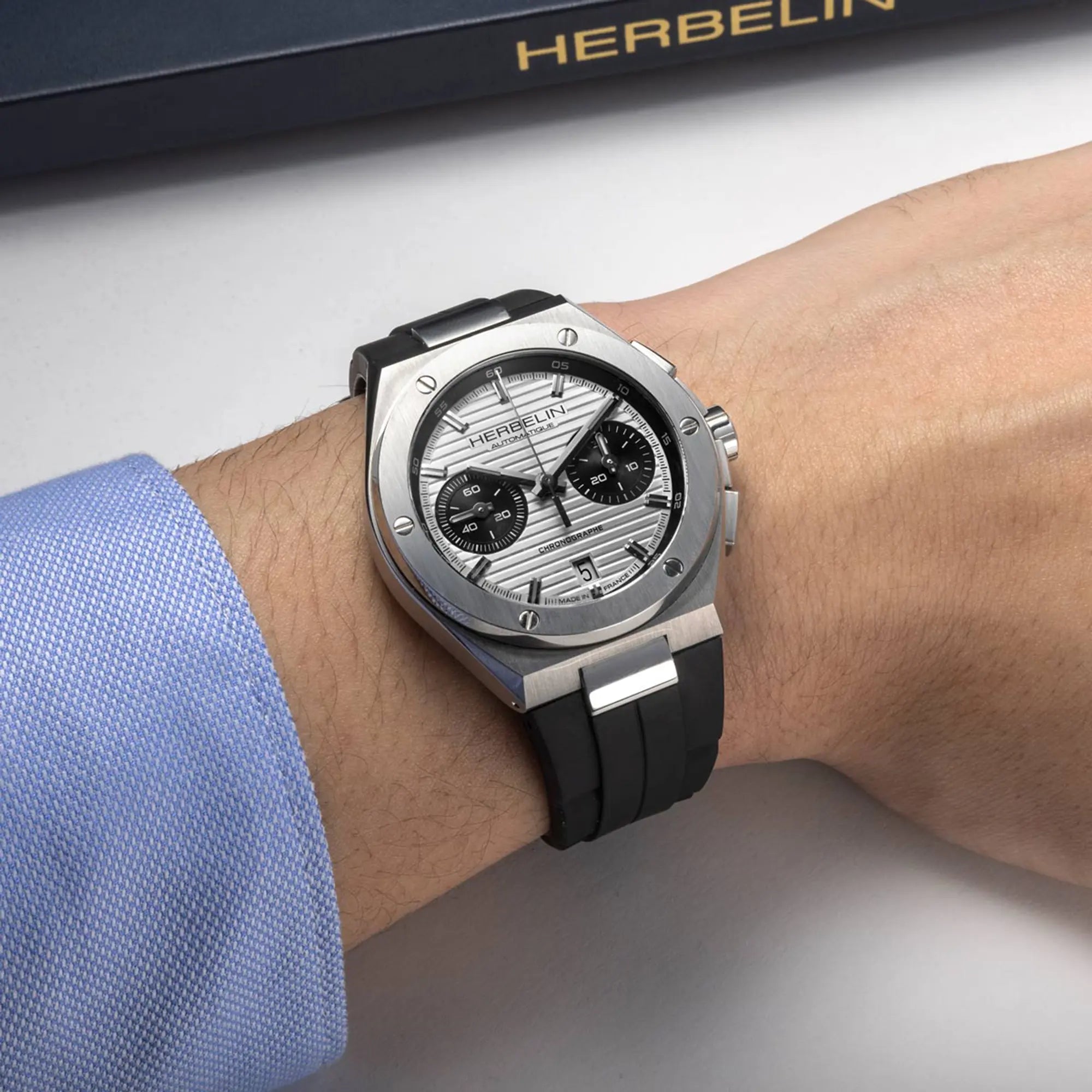 Au poignet masculin, cadran argent blanc et bracelet caoutchouc visibles