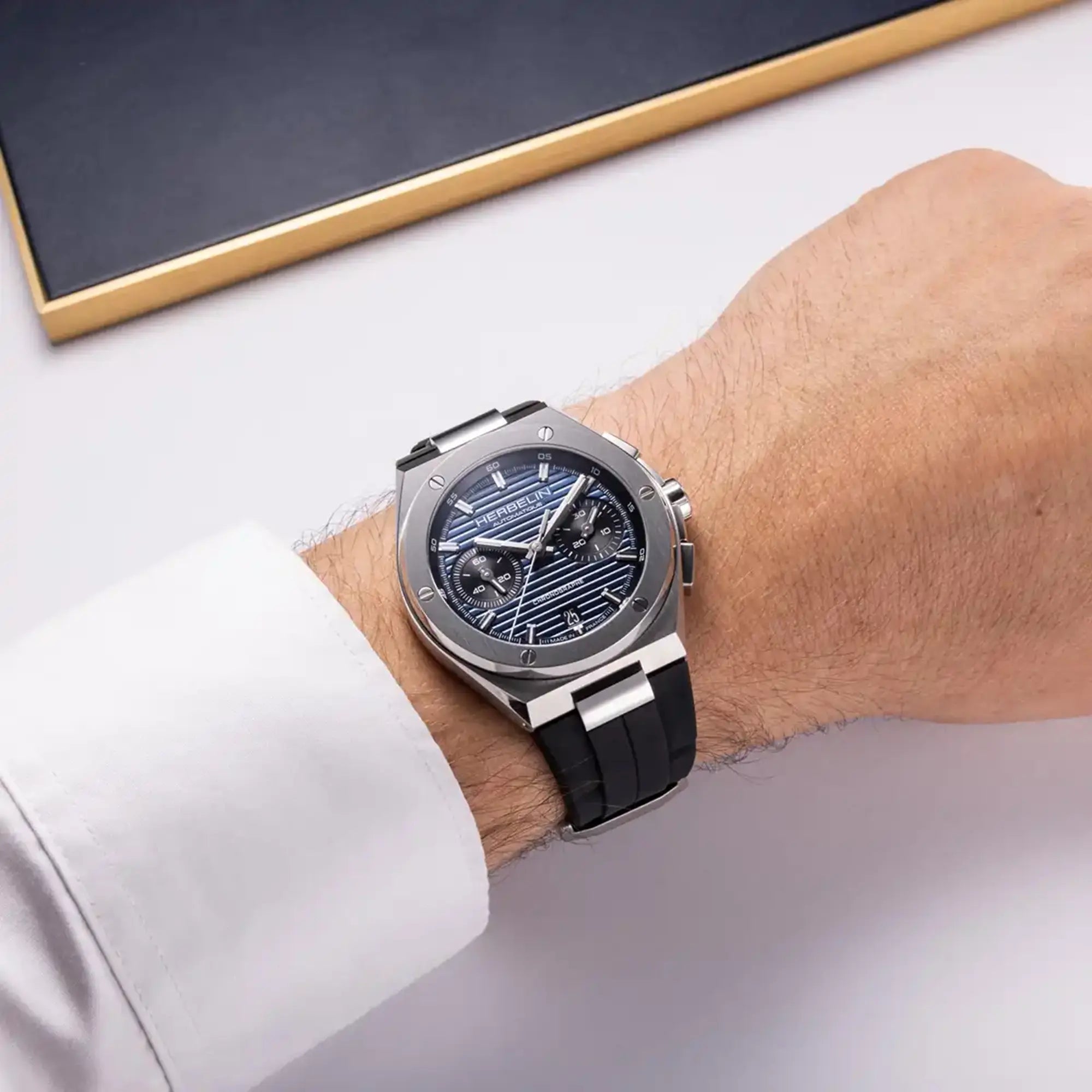 Au poignet masculin, cadran bleu et bracelet caoutchouc visibles