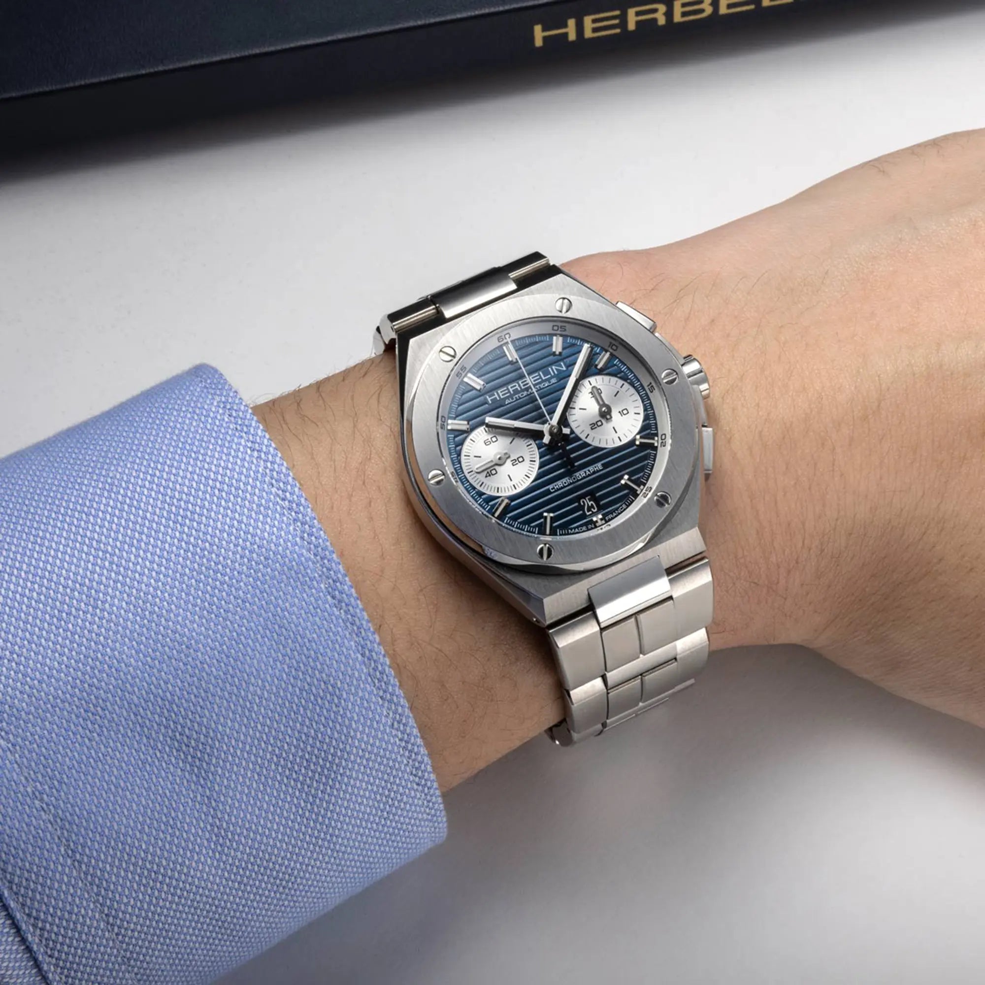 Au poignet masculin, cadran bleu et bracelet acier visibles