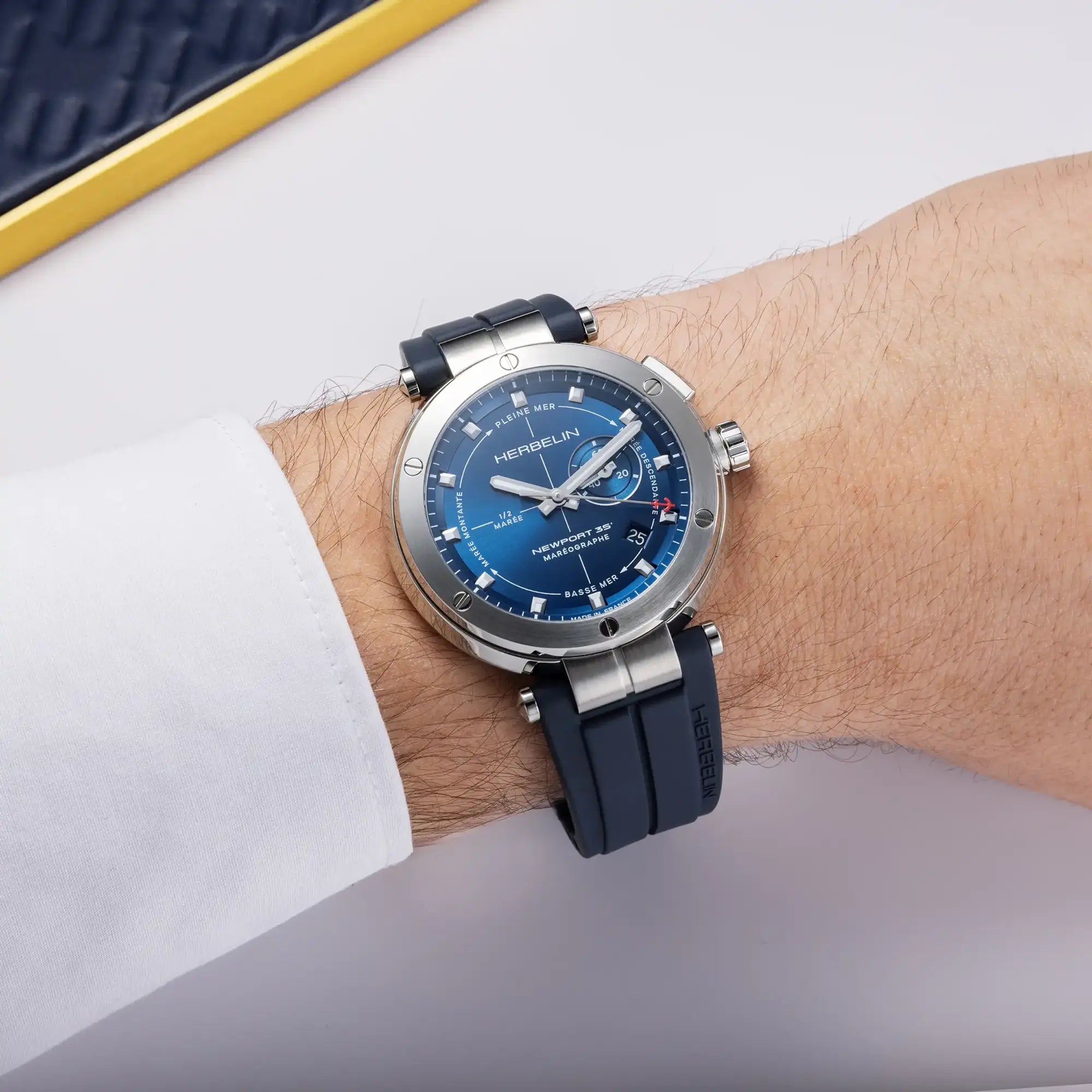 Au poignet masculin, cadran bleu et bracelet caoutchouc visibles