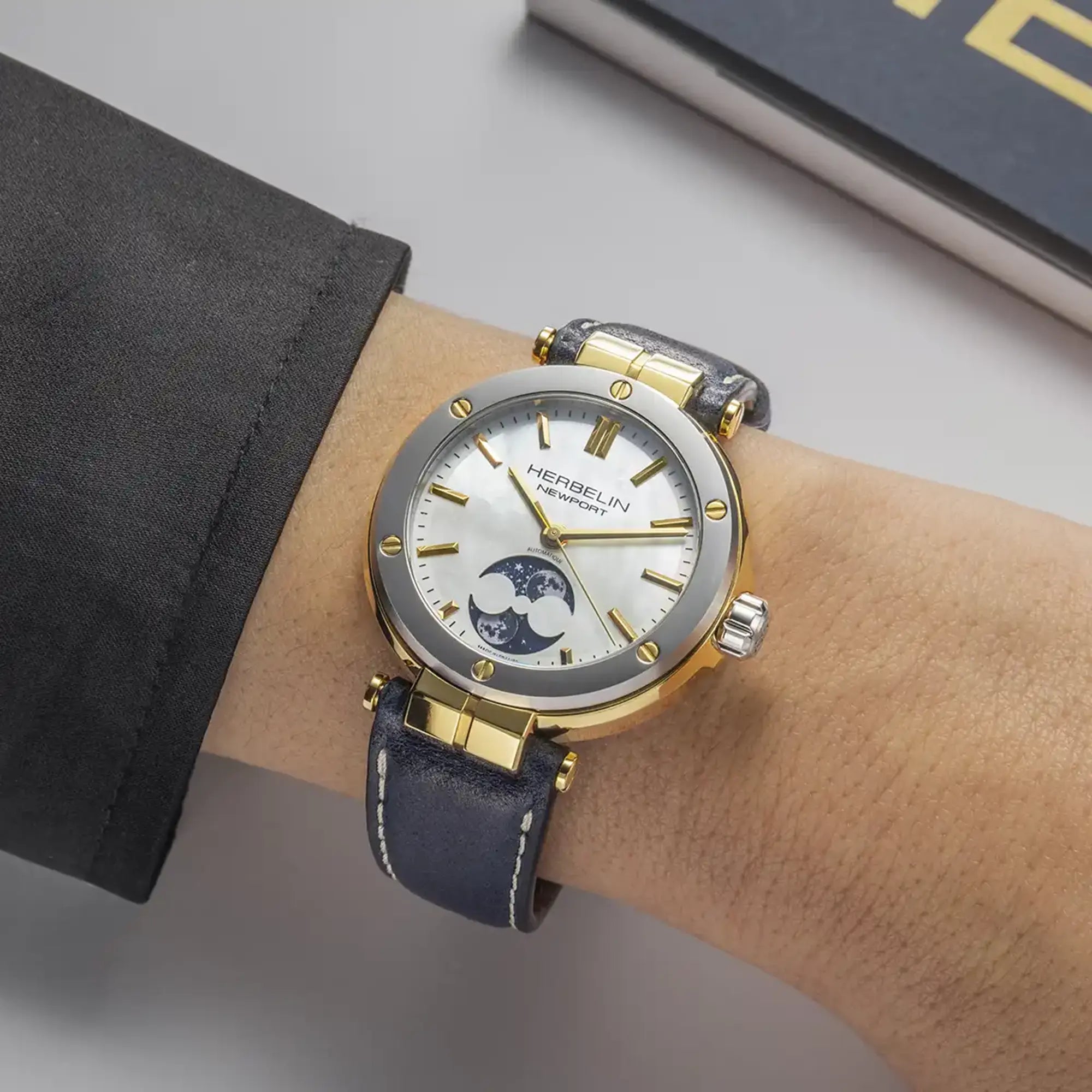 Au poignet féminin, cadran nacre blanche et bracelet cuir visibles
