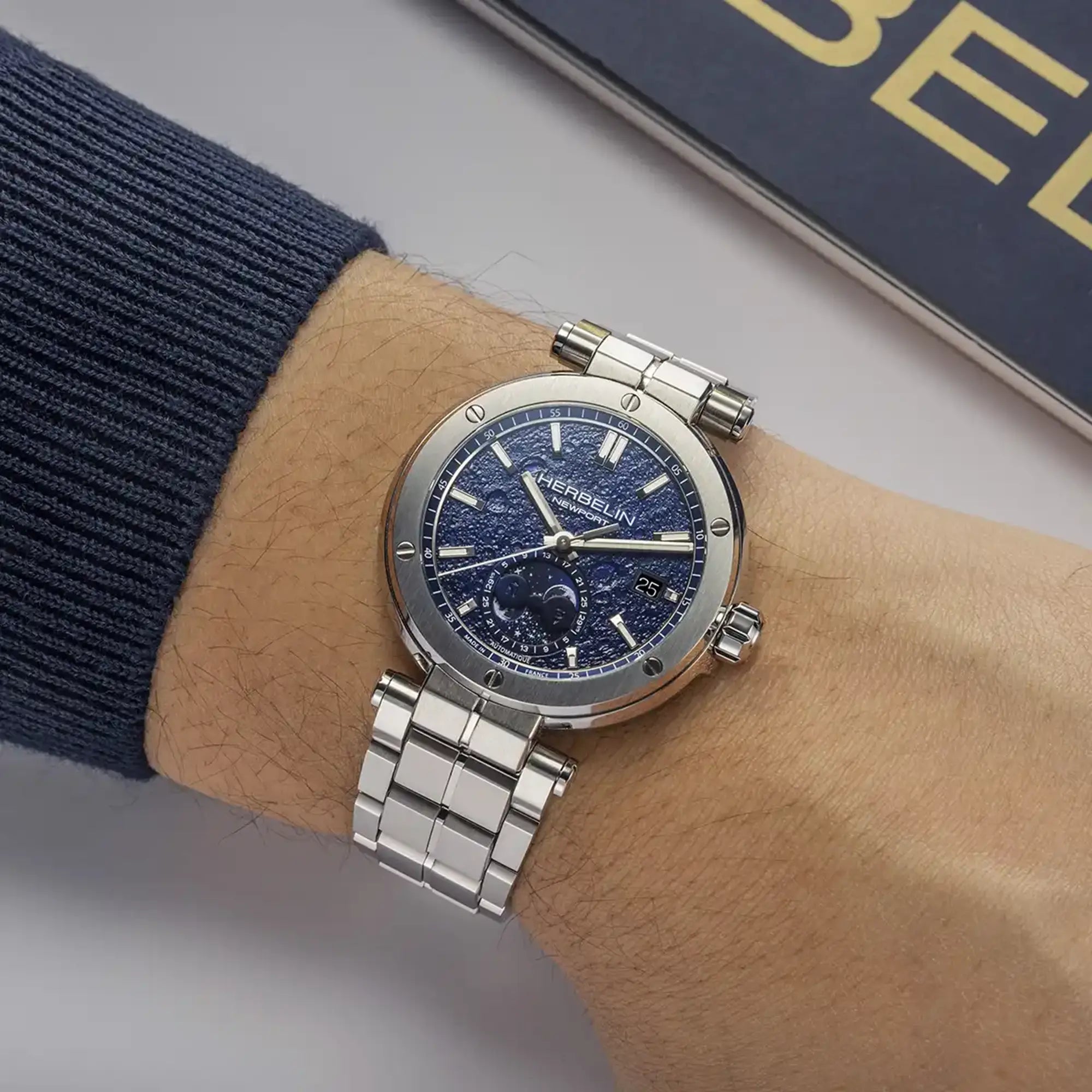 Au poignet masculin, cadran décor lunaire et bracelet acier visibles