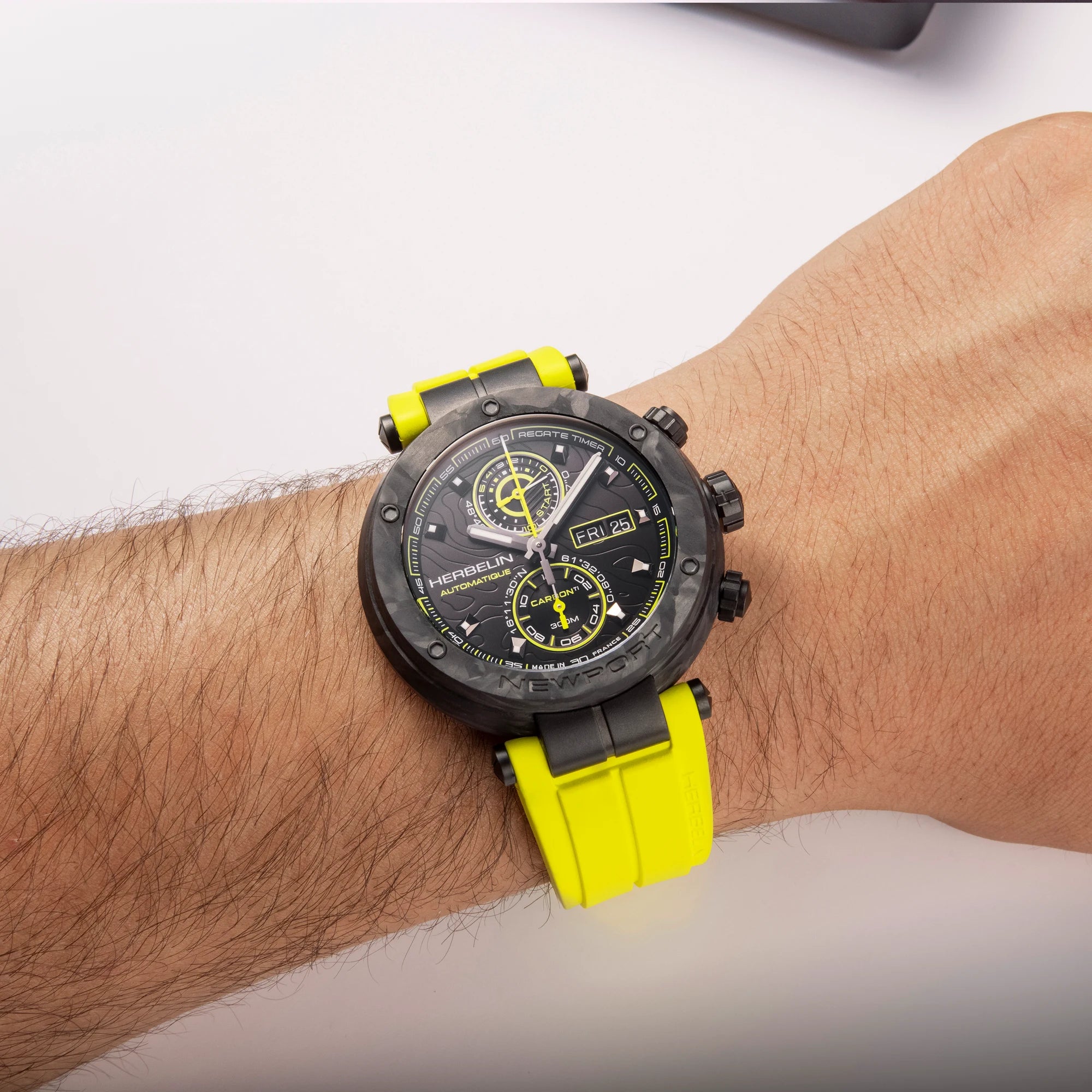 Au poignet masculin, cadran noir et jaune décor carbone, bracelet caoutchouc jaune visibles