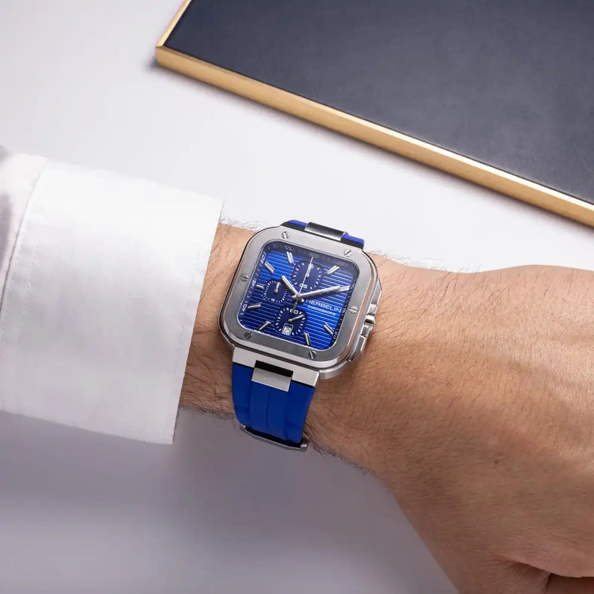 Au poignet masculin, cadran bleu cobalt et bracelet caoutchouc visibles